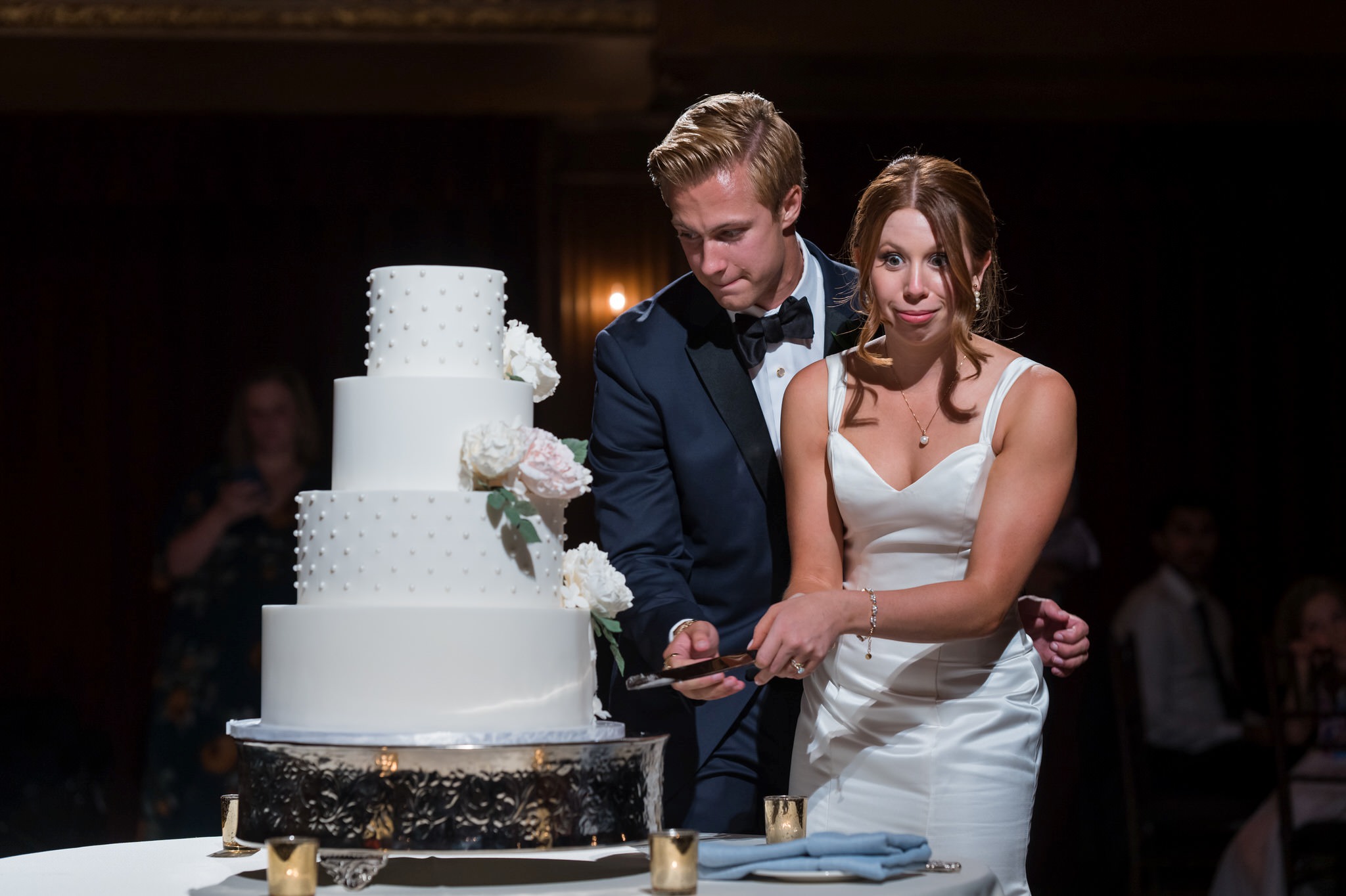A bride reacts to cutting a wedding cake during their Gem Theatre Detroit wedding.  