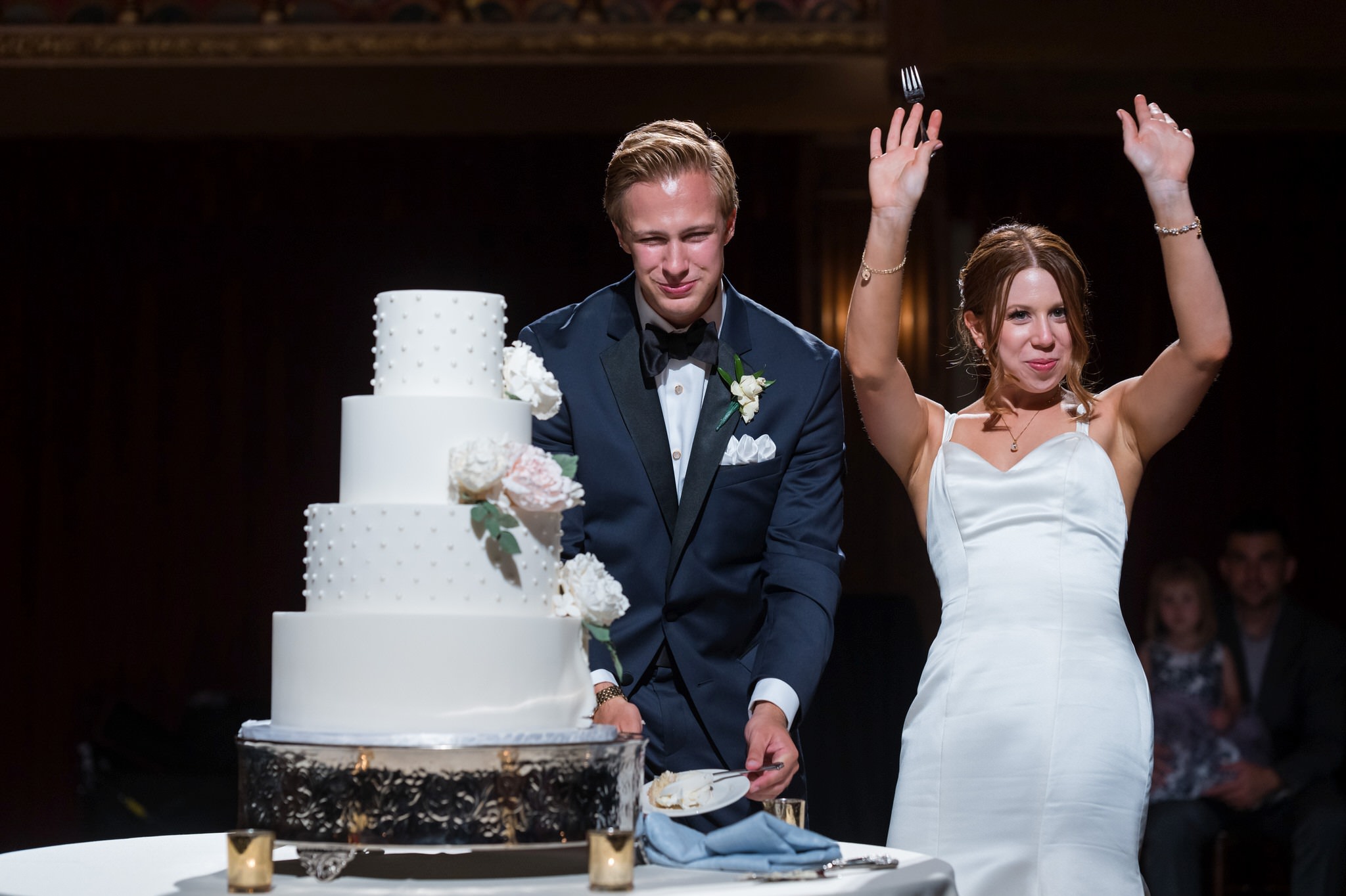 A bride and groom celebrate after eating cake during their Gem Theatre Detroit wedding.  
