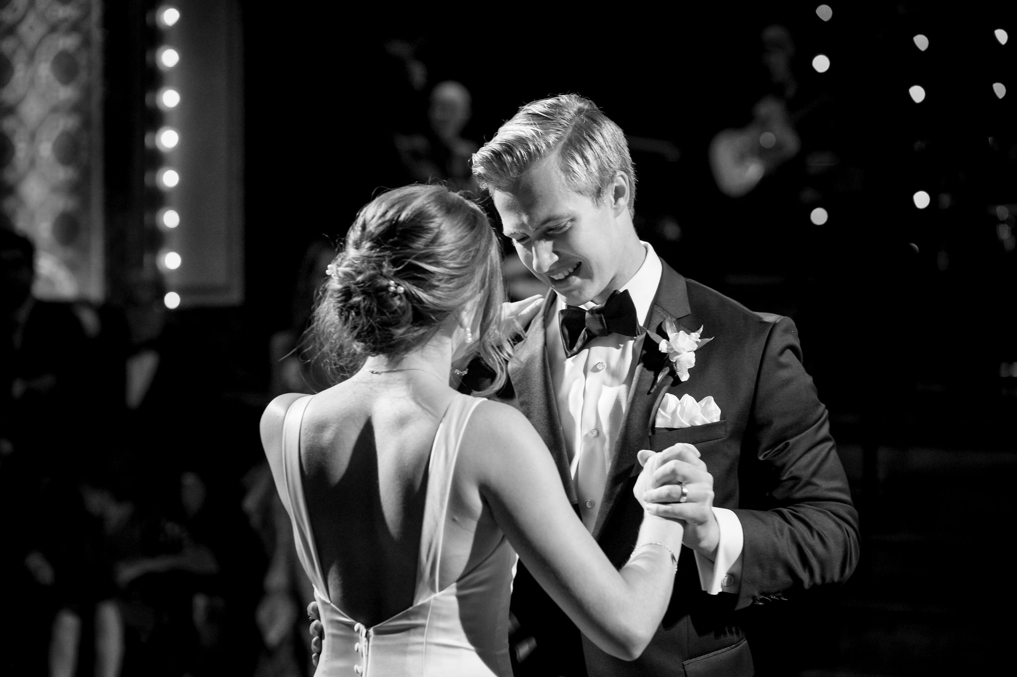 A groom, wearing a tuxedo, slow dances with the bride at a Gem Theatre Detroit Wedding. 
