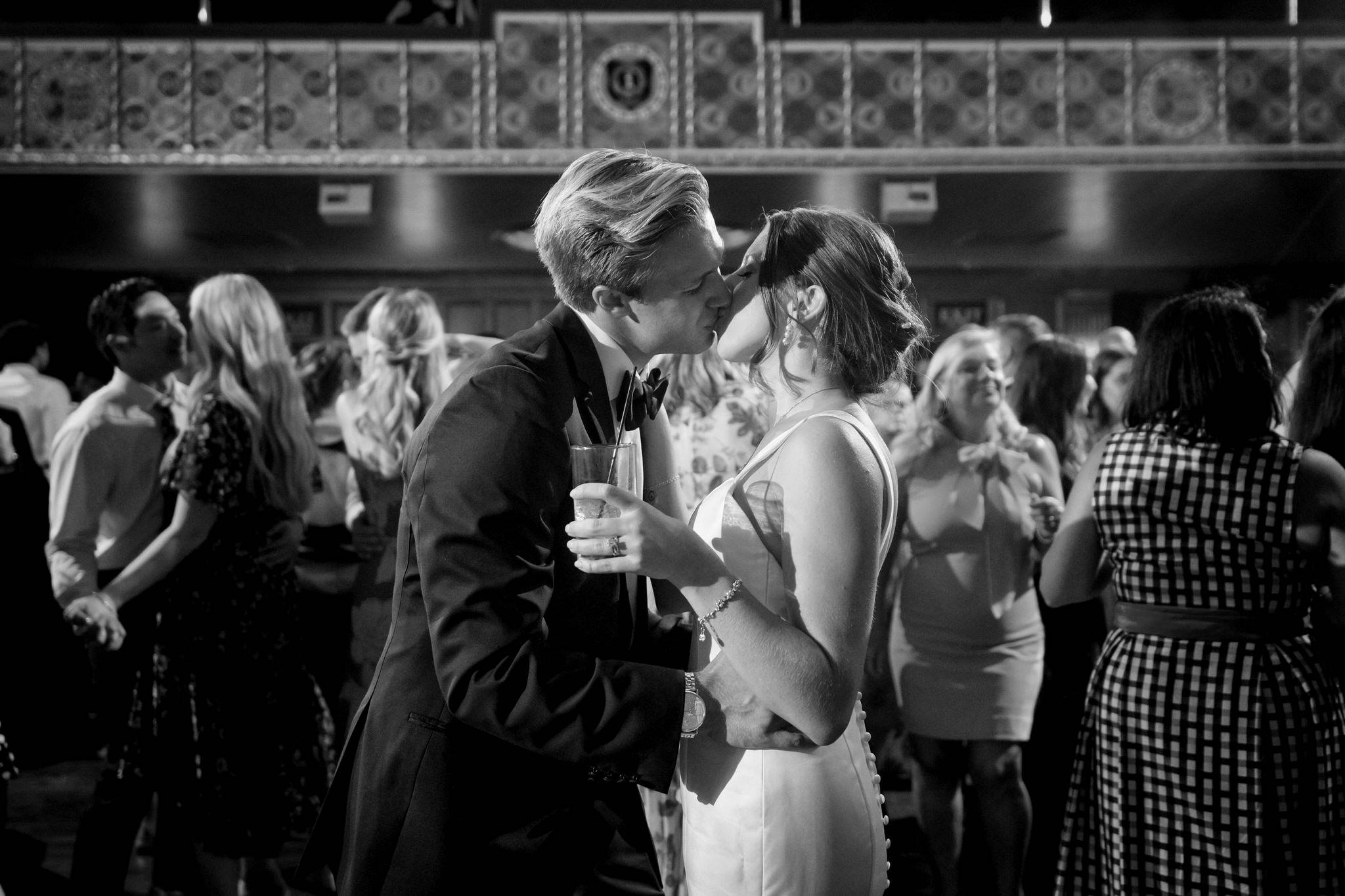 A bride and groom kiss on a crowded dance floor at their Gem Theatre Detroit wedding. 