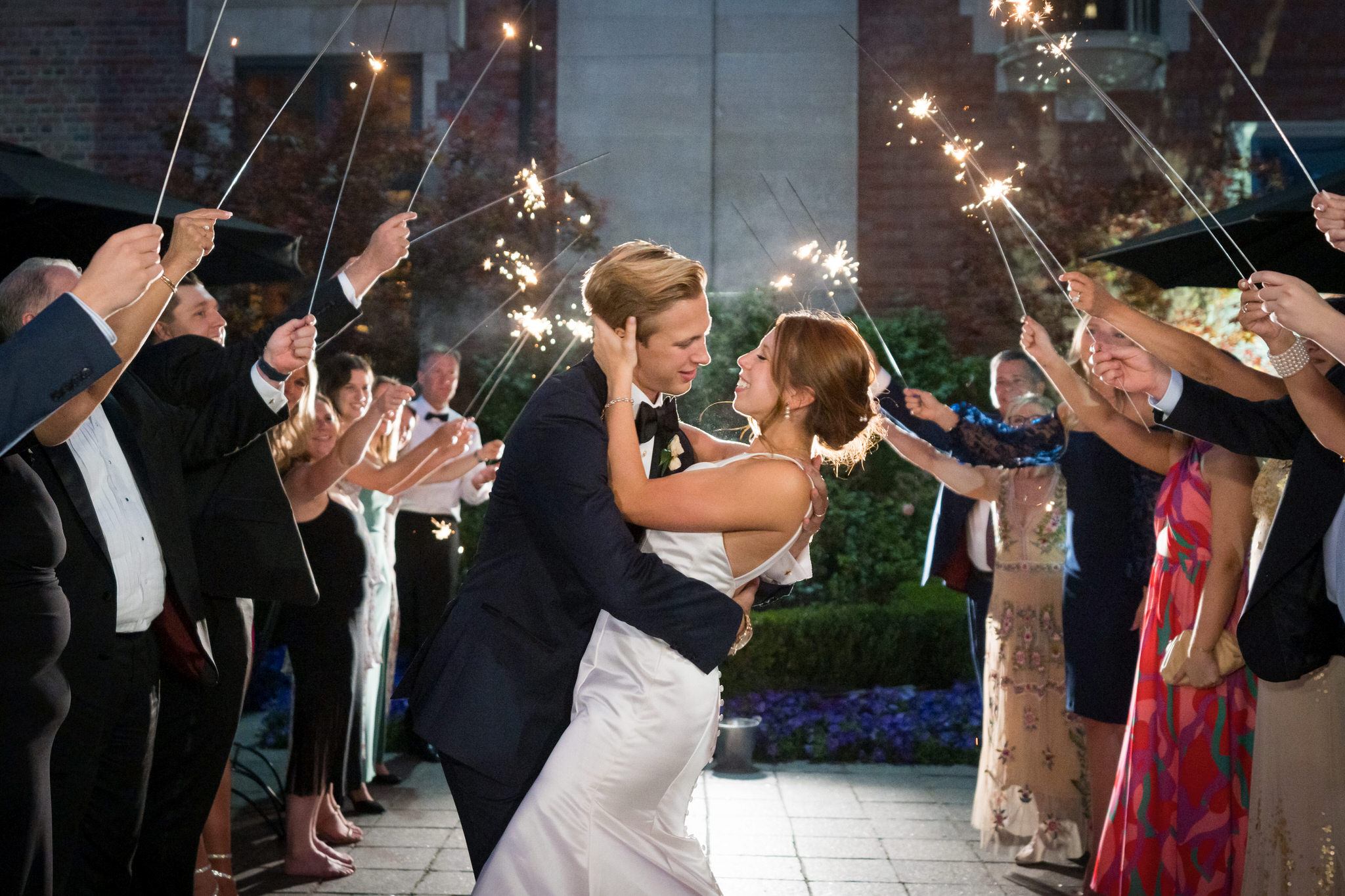 A bride and groom almost kiss inside a tunnel of sparklers outside of their Gem Theatre Detroit wedding. 