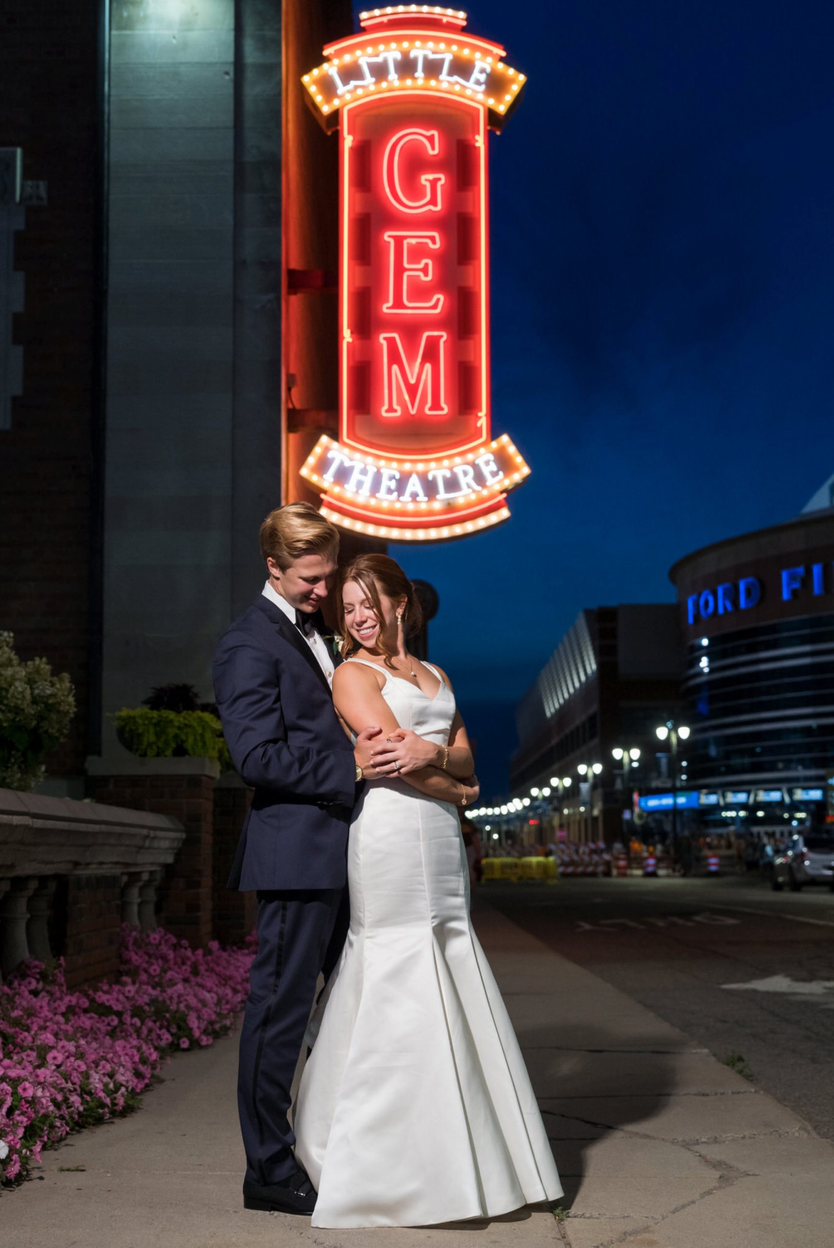 A groom holds his bride from behind his bride outside of a Gem Theatre Detroit wedding 