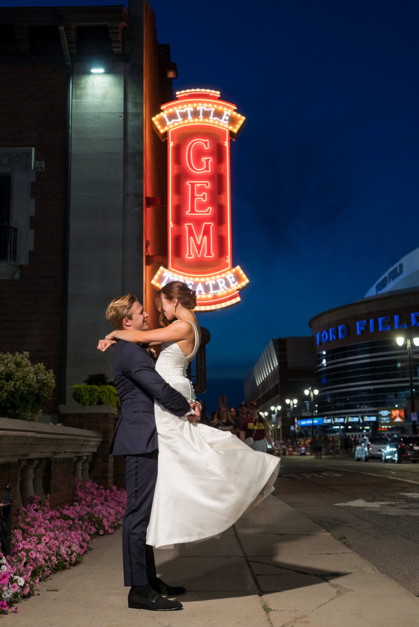A groom picks up and swings his bride outside of a Gem Theatre Detroit wedding 