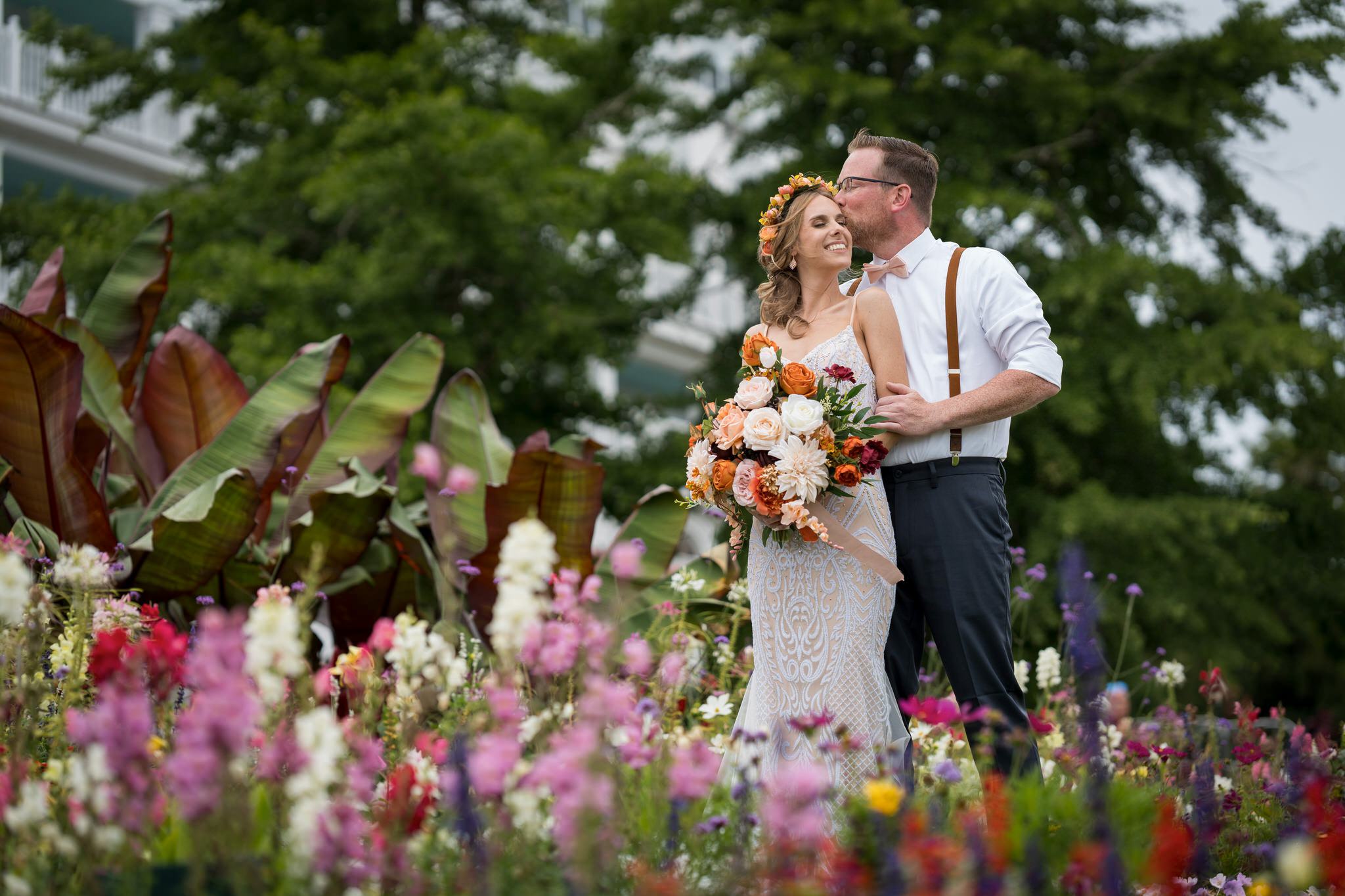 A bride and groom kiss in the flower gardens of the Grand Hotel on Mackinac Island. 
