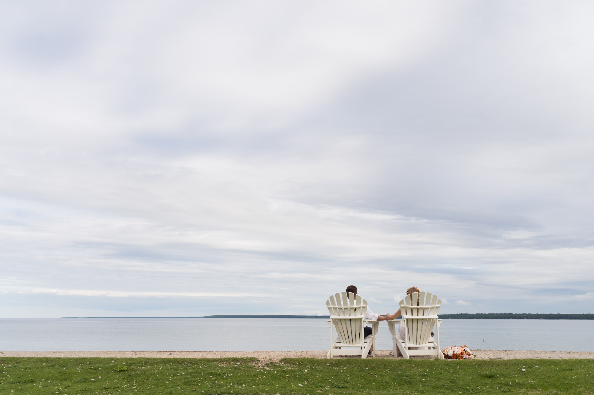 A bride and groom sit on adirondack chair on Mackinac Island.