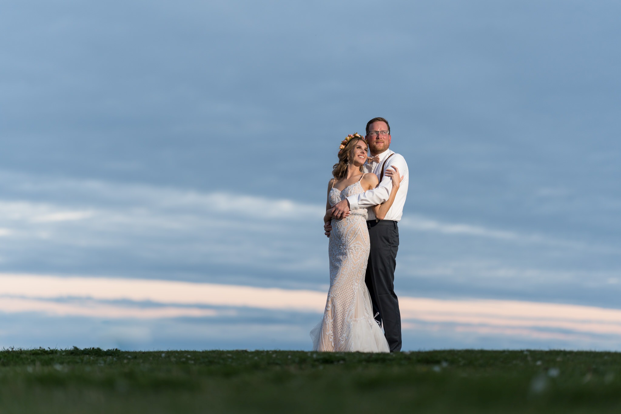 The groom hugs the bride from behind at sunset at their Mission Pointe Resort wedding.