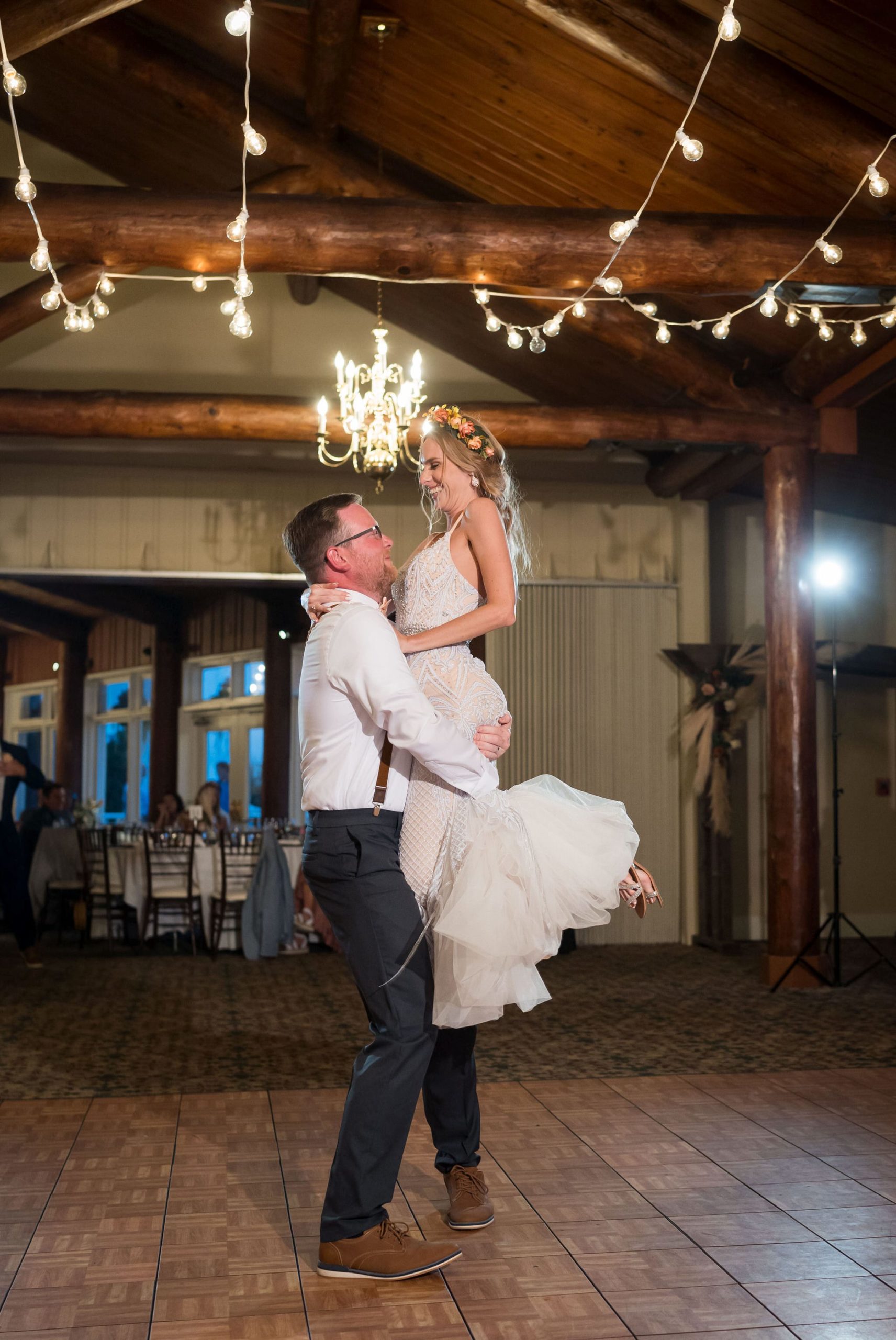 A groom lifts a bride into the air on the dance floor at their Mission Pointe Resort wedding.