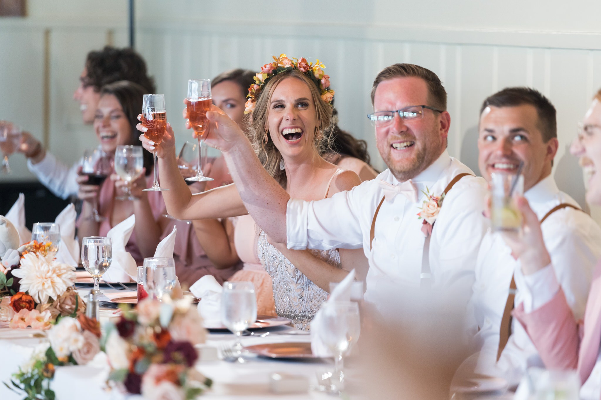 A bride and groom hold champagne glasses and toast during speeches at a Mission Pointe Resort wedding.