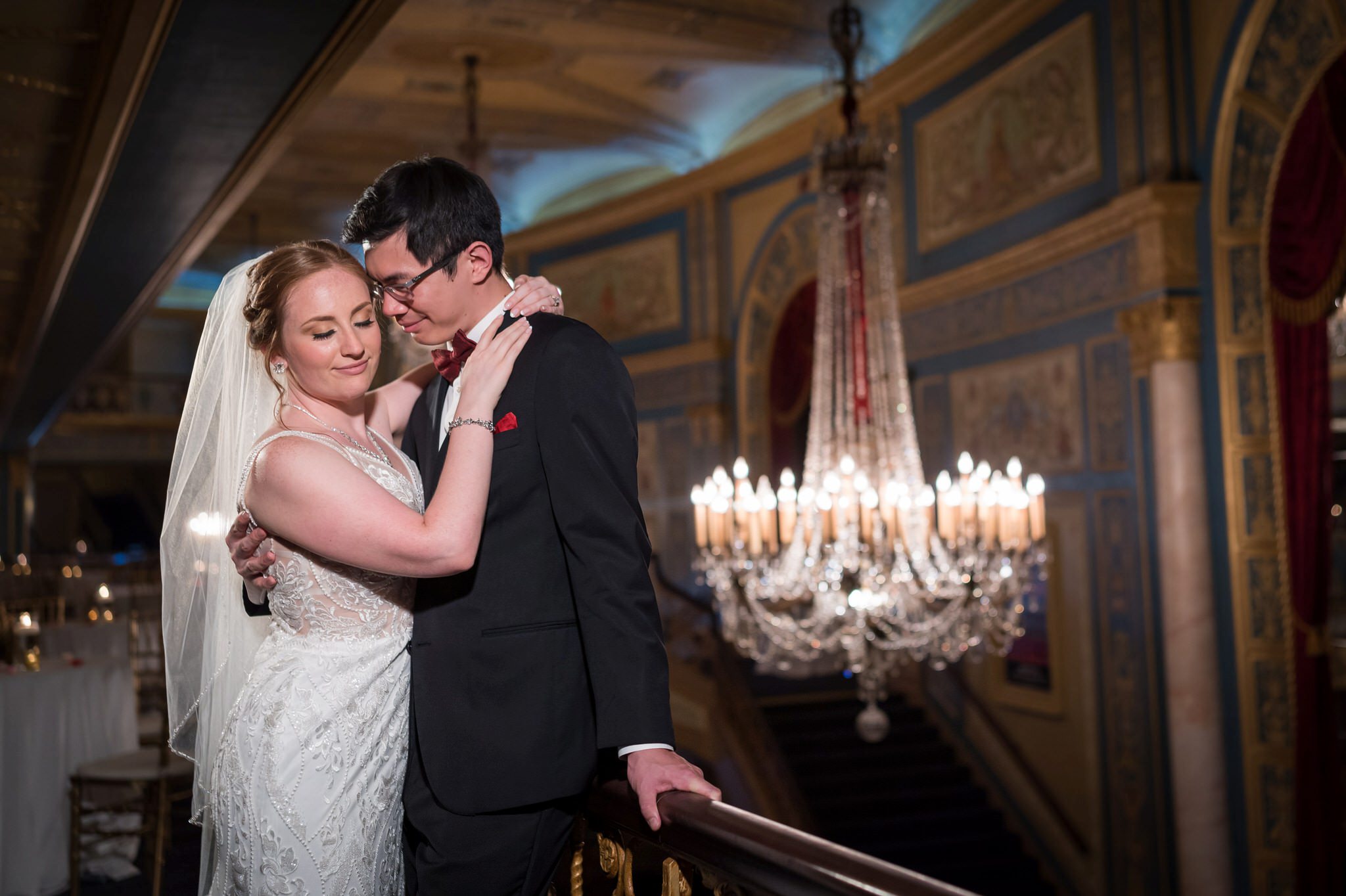 A bride and groom close their eyes and hug on the grand staircase at the Detroit Opera House. 