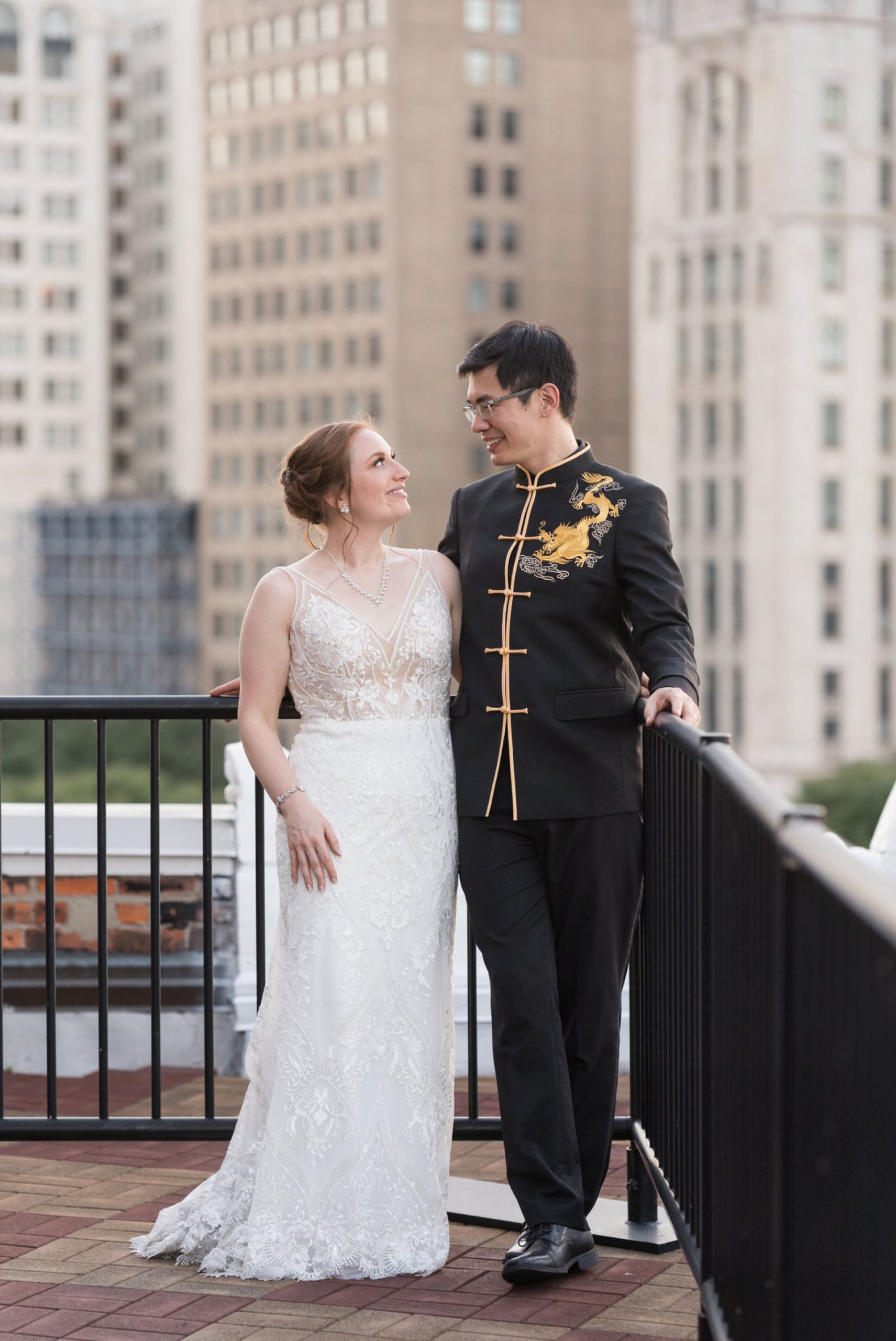 A bride and groom stand next to each other at their rooftop wedding at Detroit Opera House. 