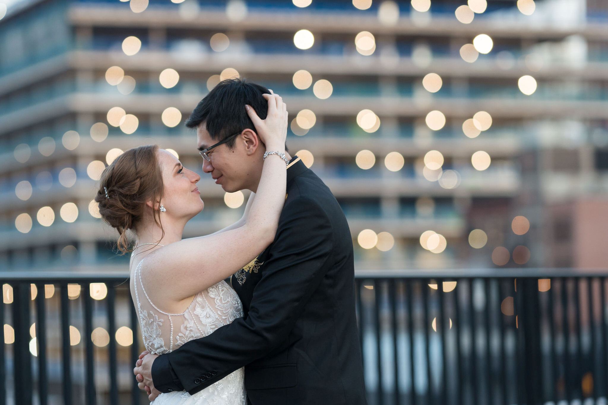 A bride and groom closely embrace on top of the Detroit Opera House. 