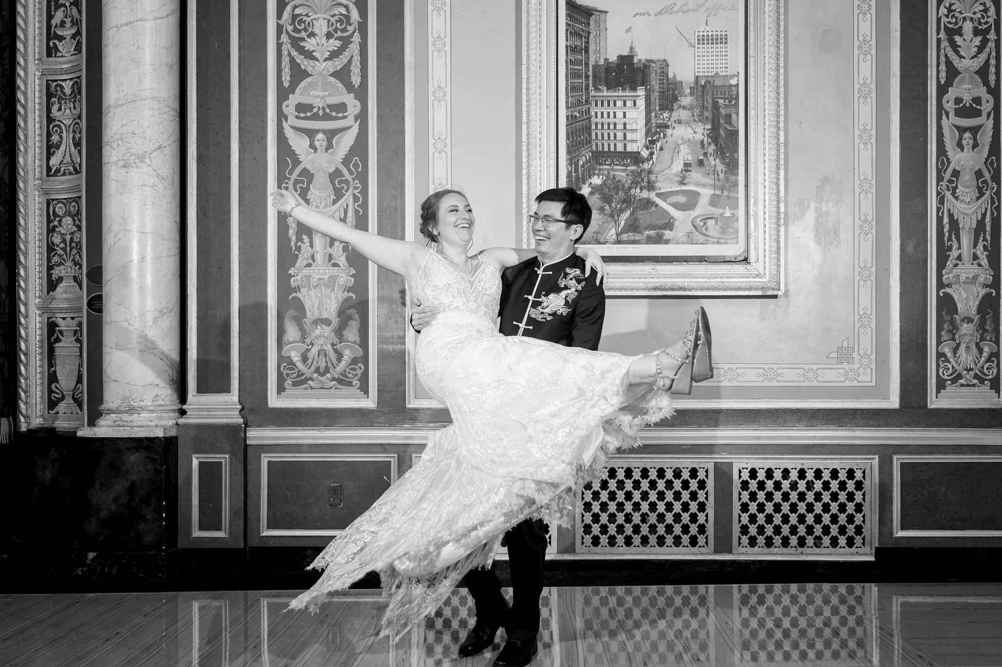 A black and white photo of a bride being lifted by her groom on the dance floor of the Detroit Opera House. 