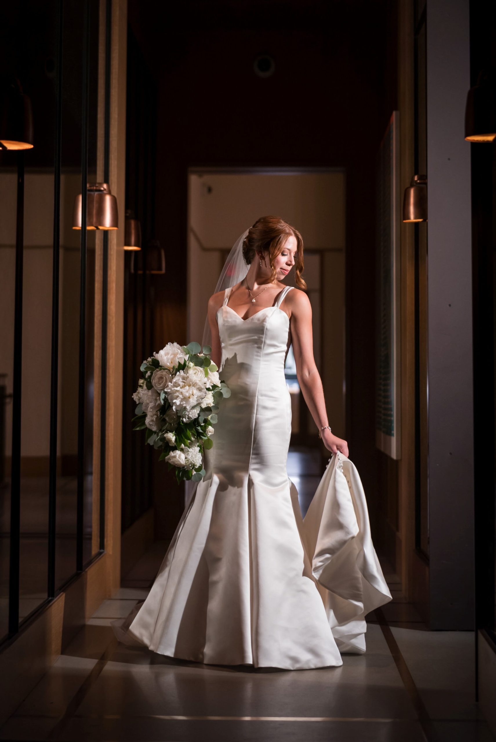 A bride looks down at her dress in the hallway of the Shinola Hotel in Detroit. 