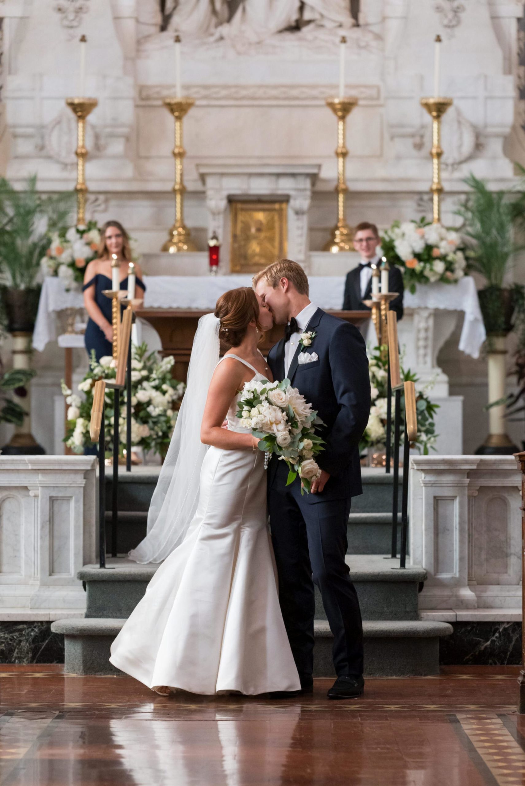 A bride and groom kiss in the aisle at their wedding at Saints Peter and Paul Jesuit Church in Detroit.  