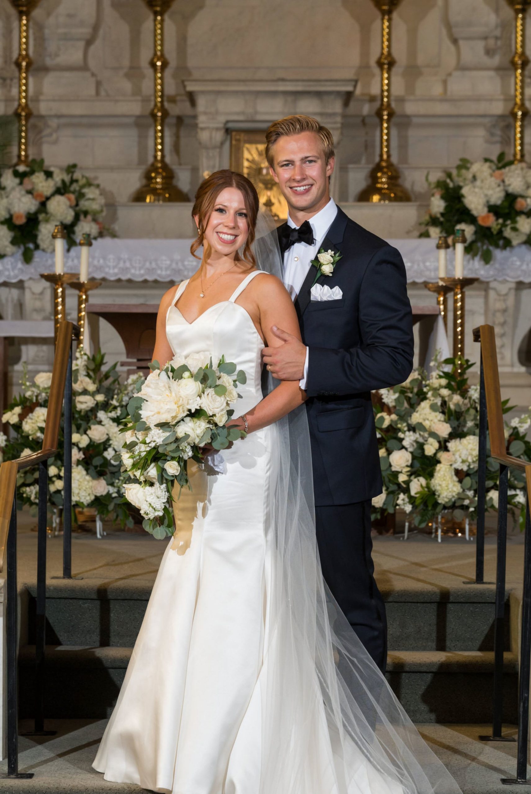 A bride and groom pose for a formal photo at the altar of Saints Peter and Paul Jesuit Church in Detroit. 