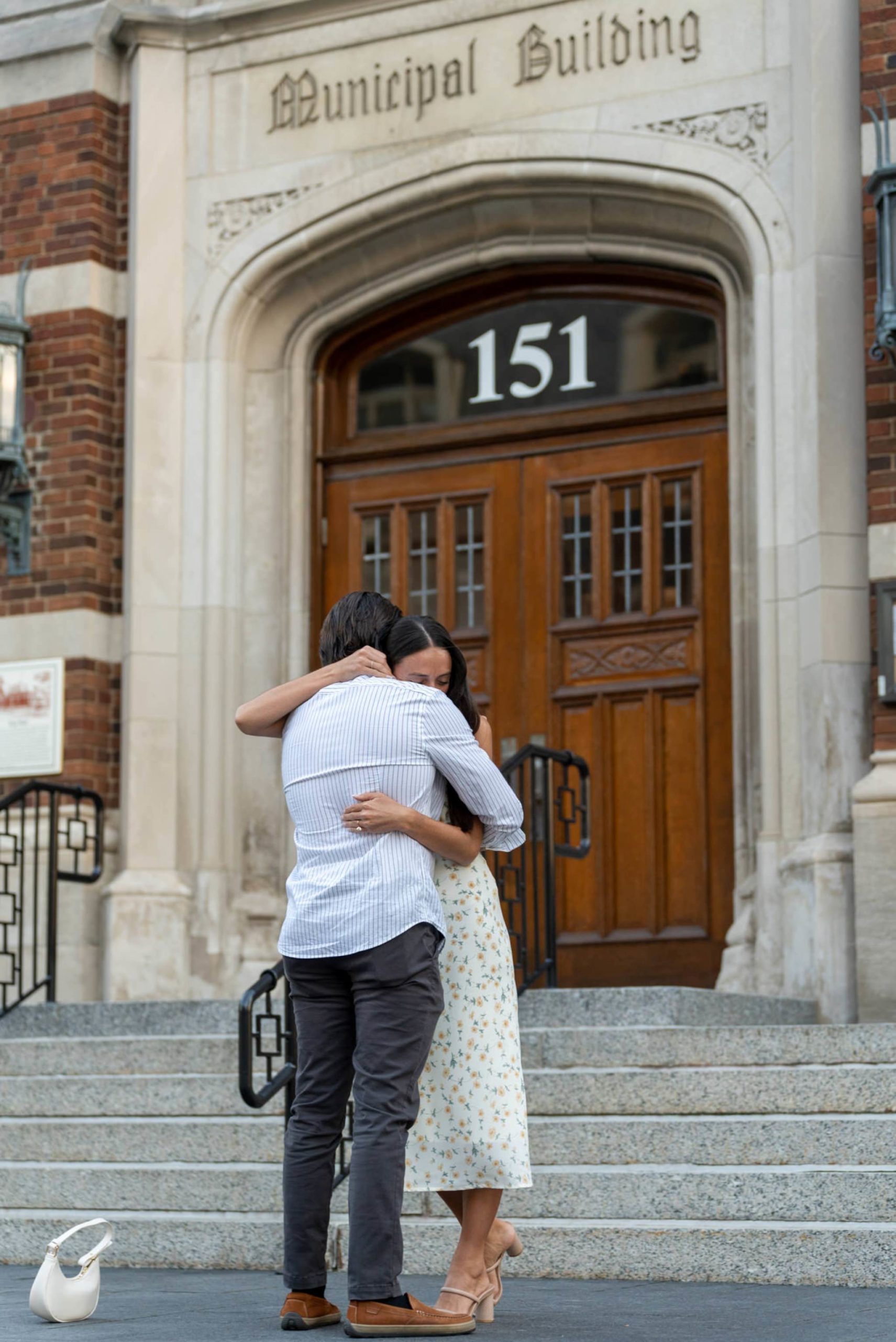 a man and woman tightly hug outside of the municipal building during his downtown Birmingham proposal