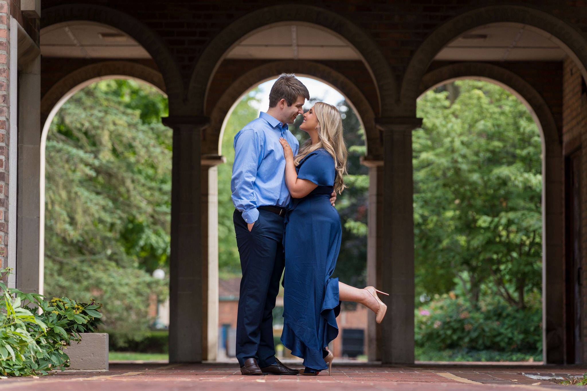 A couple stand in the arches at the Cranbrook Institute or Art during their engagement session.  