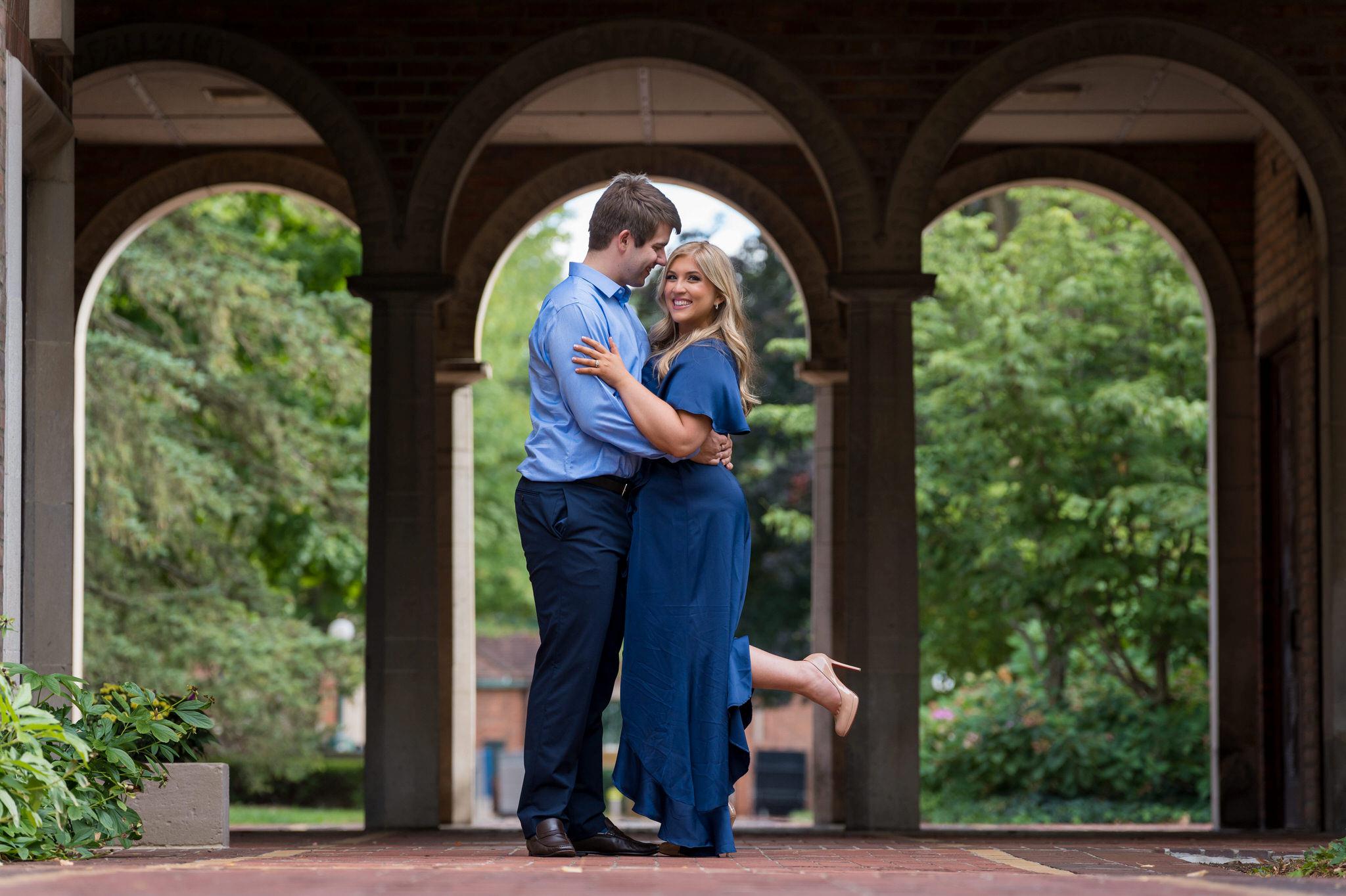 A couple stand in the arches at the Cranbrook Institute or Art during their engagement session.  