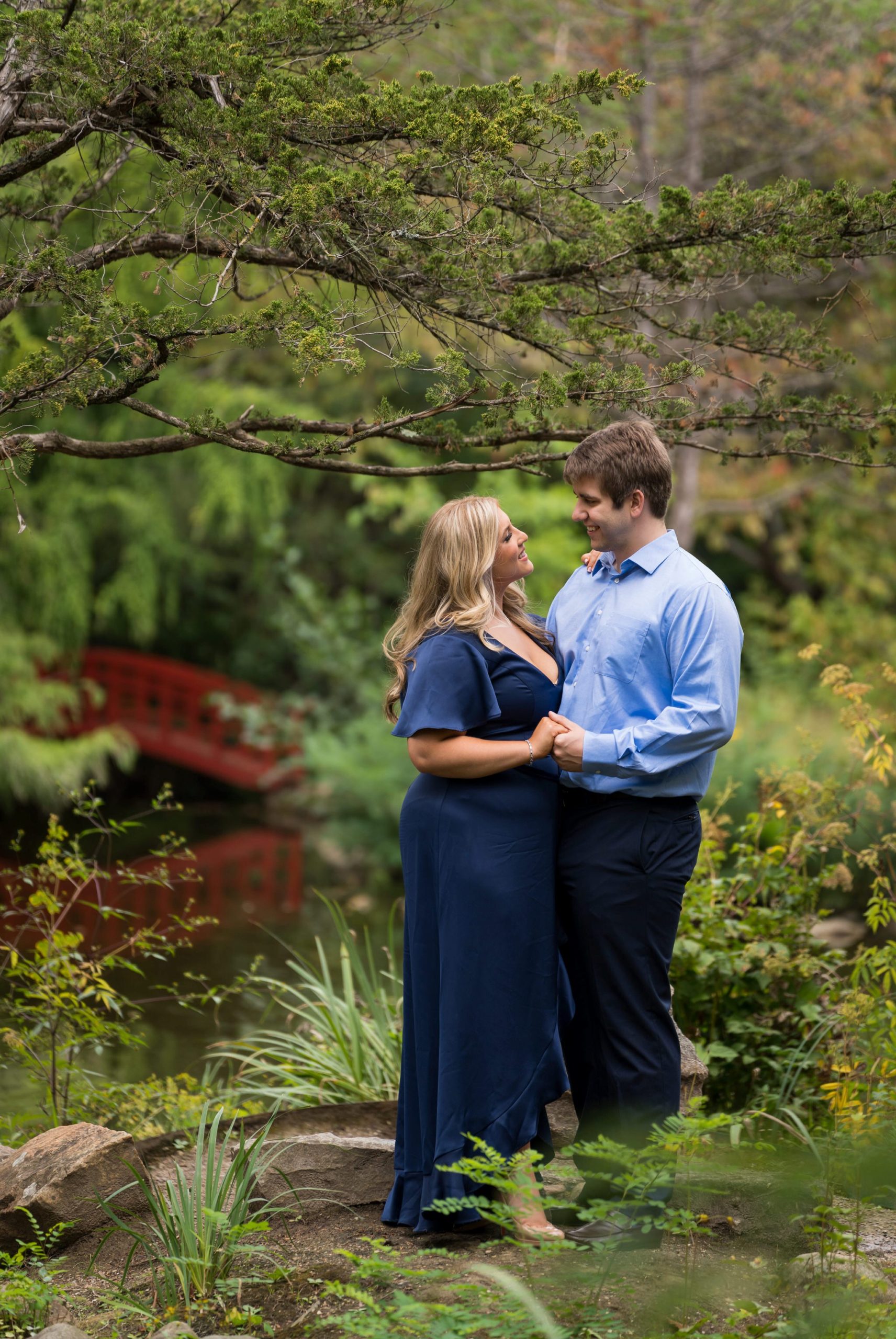 A couple holds hands on a small island in the Cranbrook Japanese Gardens during their Cranbrook engagement session.  