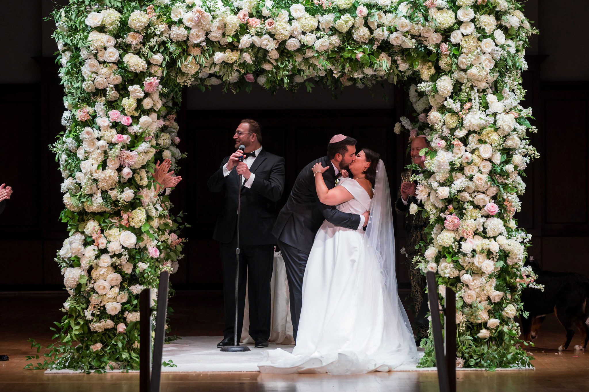 A jewish bride and groom kiss under a white chuppah at the Detroit Orchestra Hall wedding.  