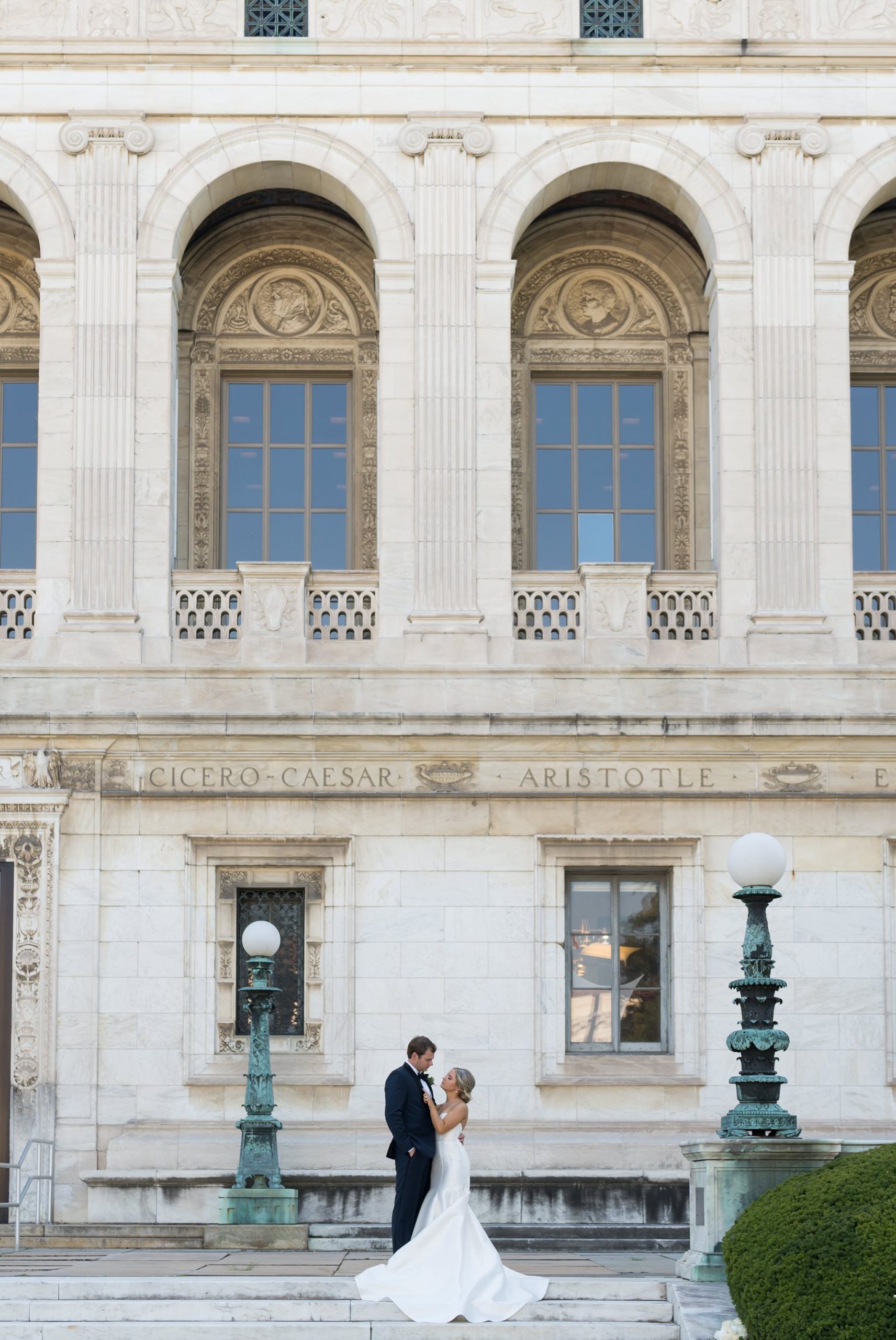 A bride holds the lapel of her groom's jacket on the steps of the Detroit Public Library.  