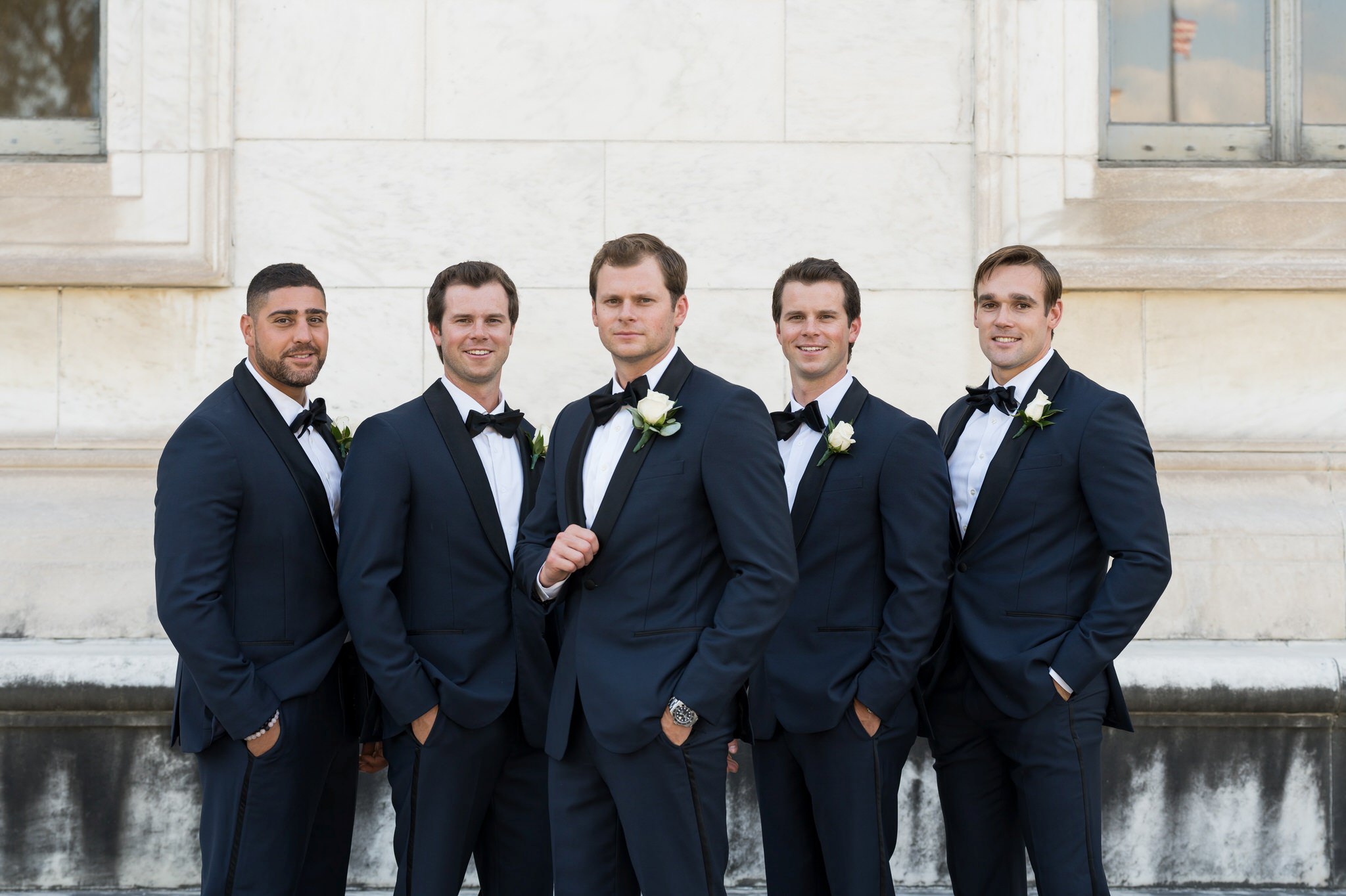 Groomsmen in blue and black tuxes pose outside of the Detroit Public Library.  