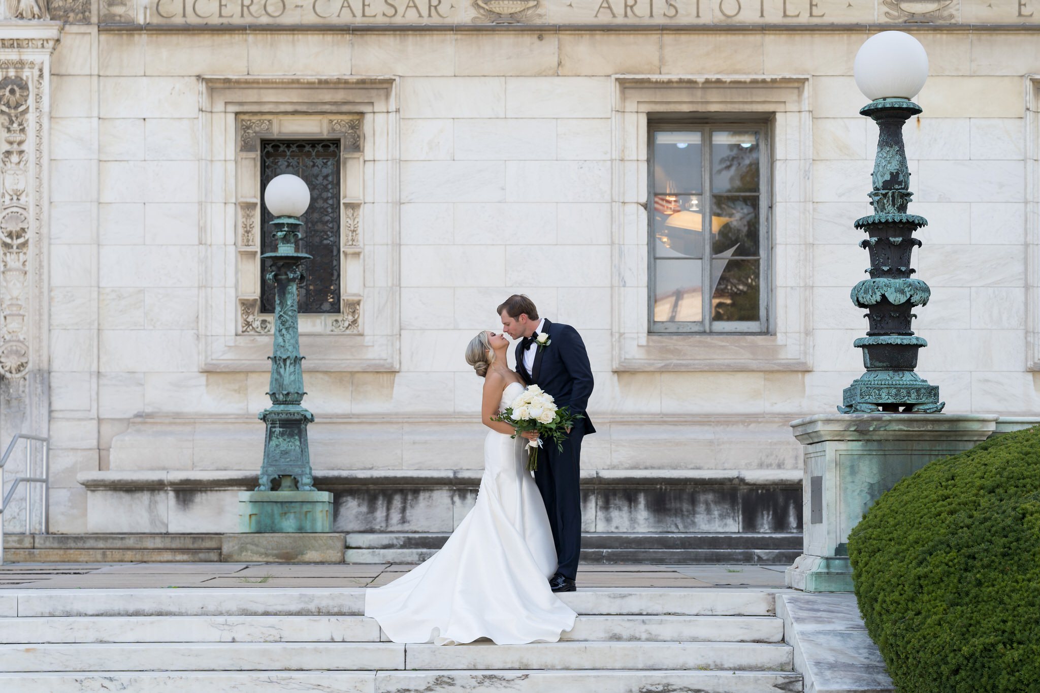 Bride and groom almost kiss while stand on white marble steps of the Detroit Public Library. 