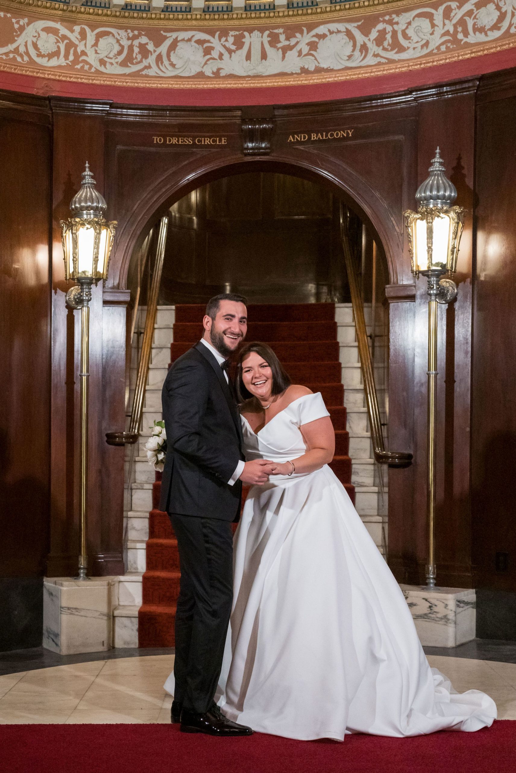 A bride and groom laugh in oval entrance to their Detroit Orchestra Hall wedding.