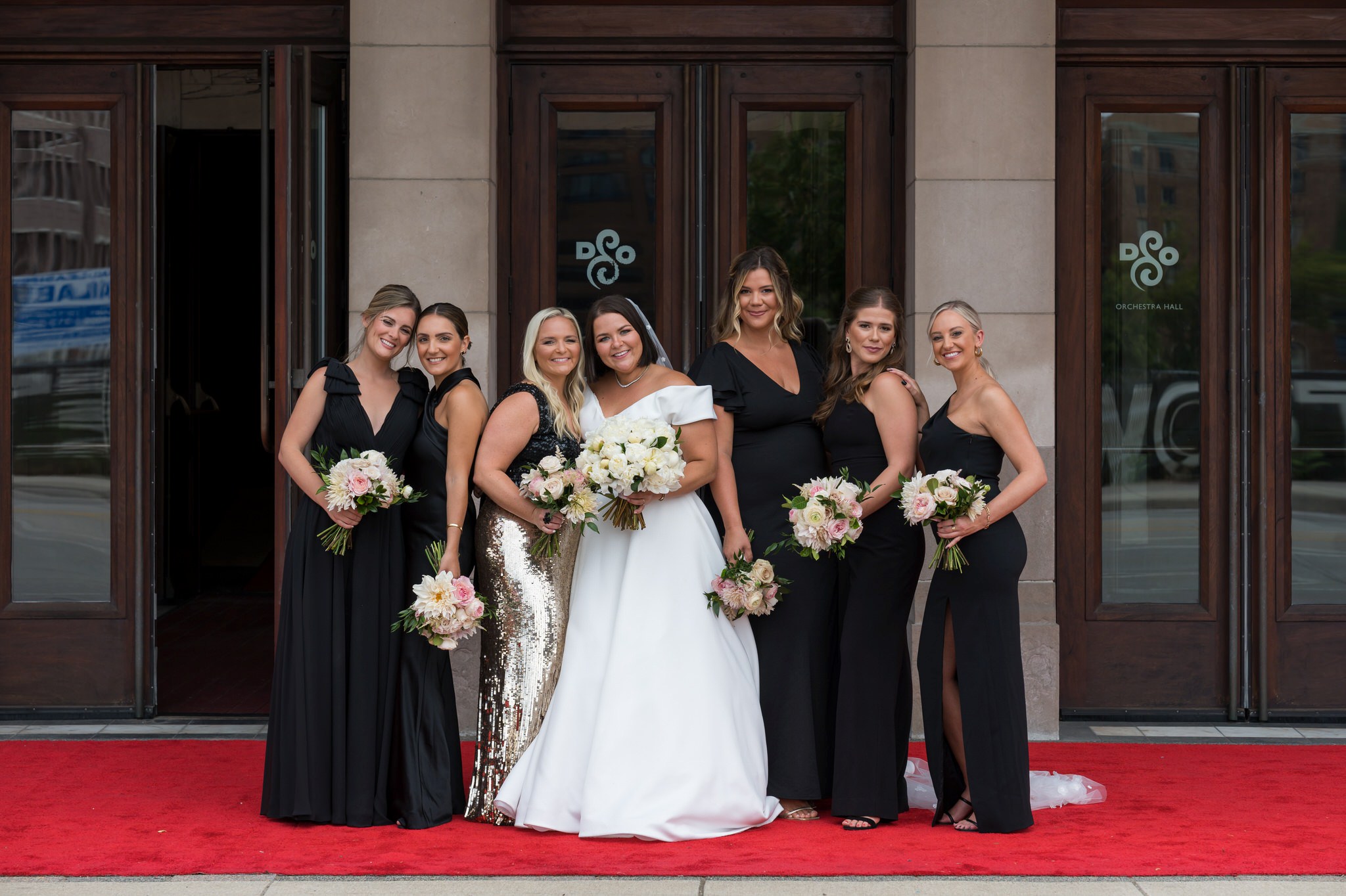 Bridesmaids pose outside the a Detroit Orchestra Hall wedding on red carpet.
