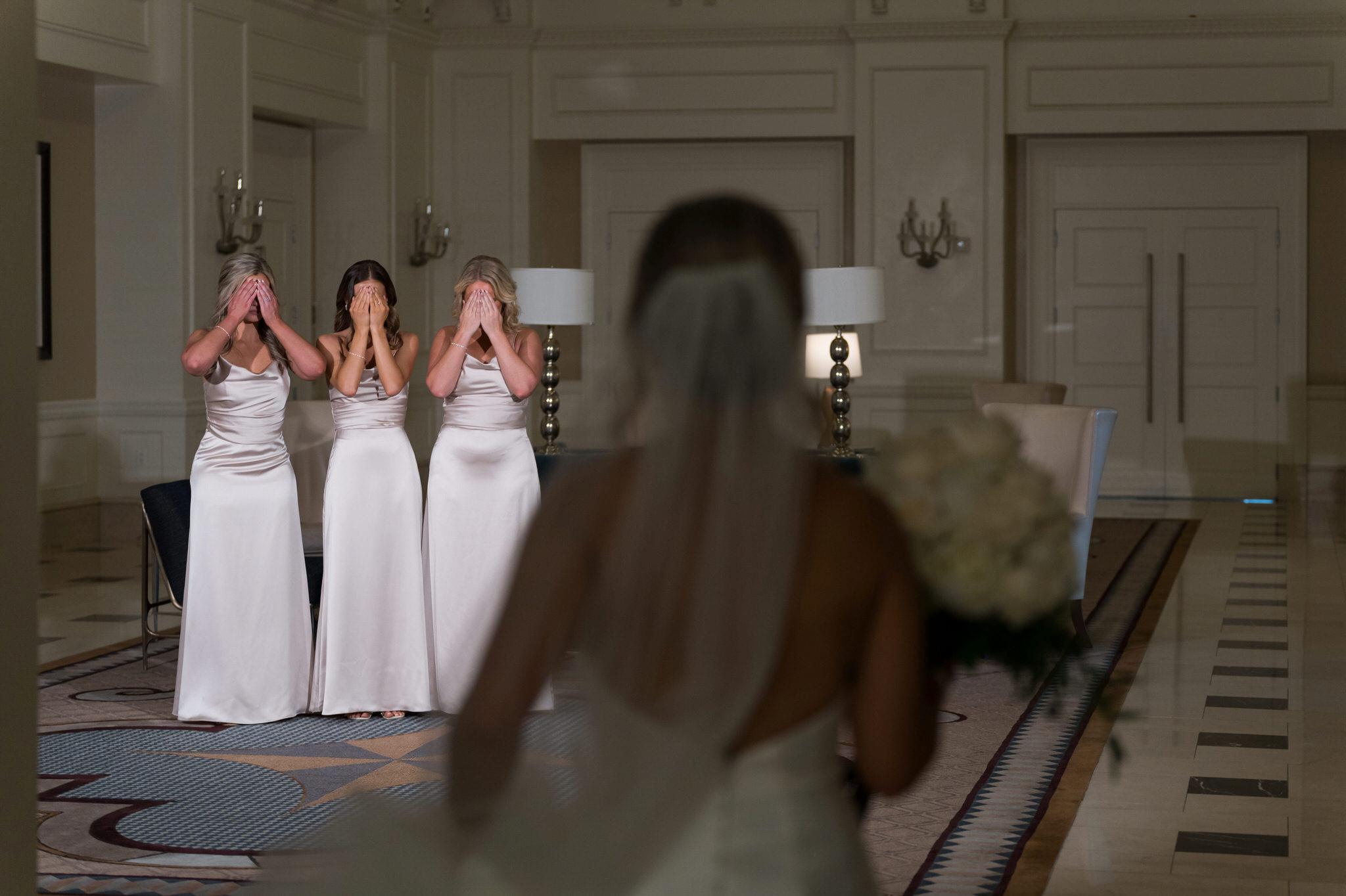Bridesmaids cover their eyes before seeing a bride for the first time.  