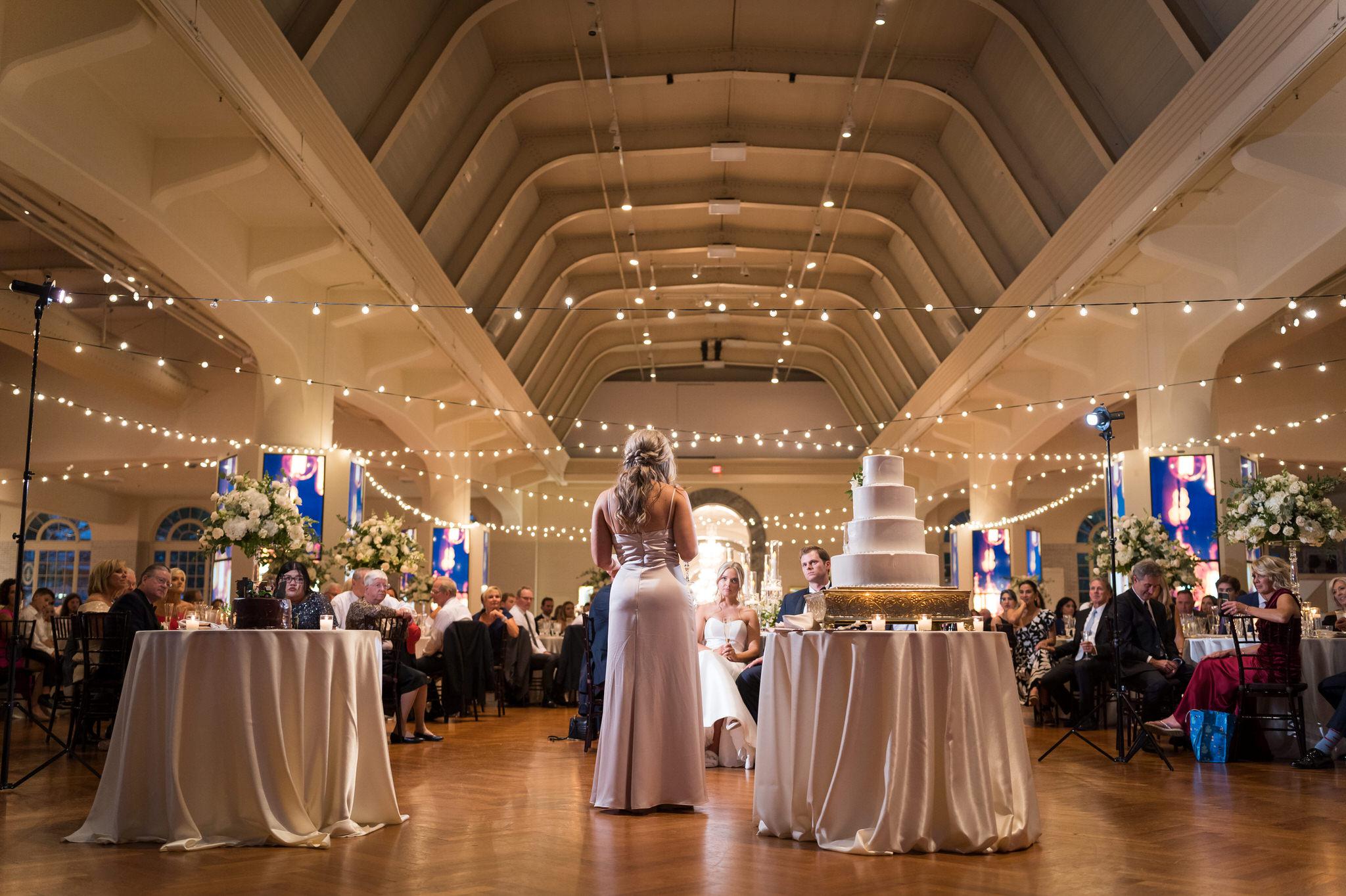 The view from behind of a bridesmaid giving a speech at a Henry Ford Museum wedding. 