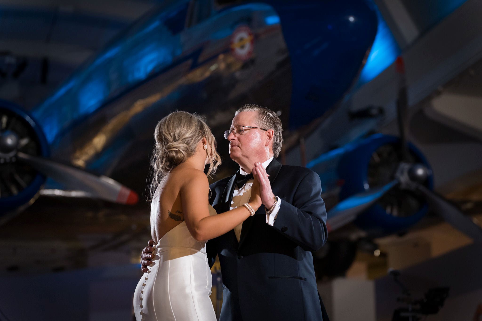A father and his daughter share a first dance under an airplane at a Henry Ford Museum wedding. 