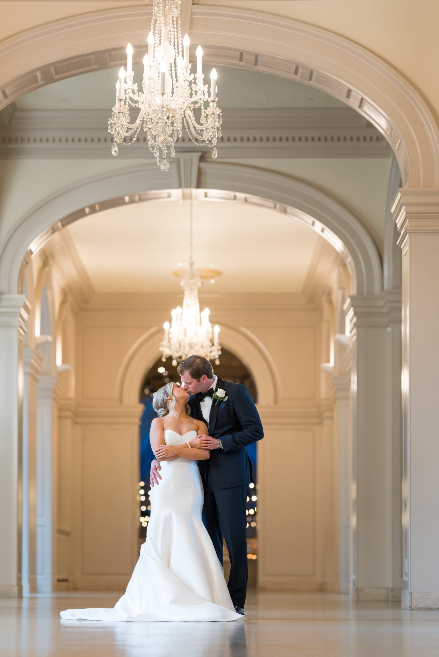 A bride and groom kiss in the arched hallway at their Henry Ford Museum wedding. 