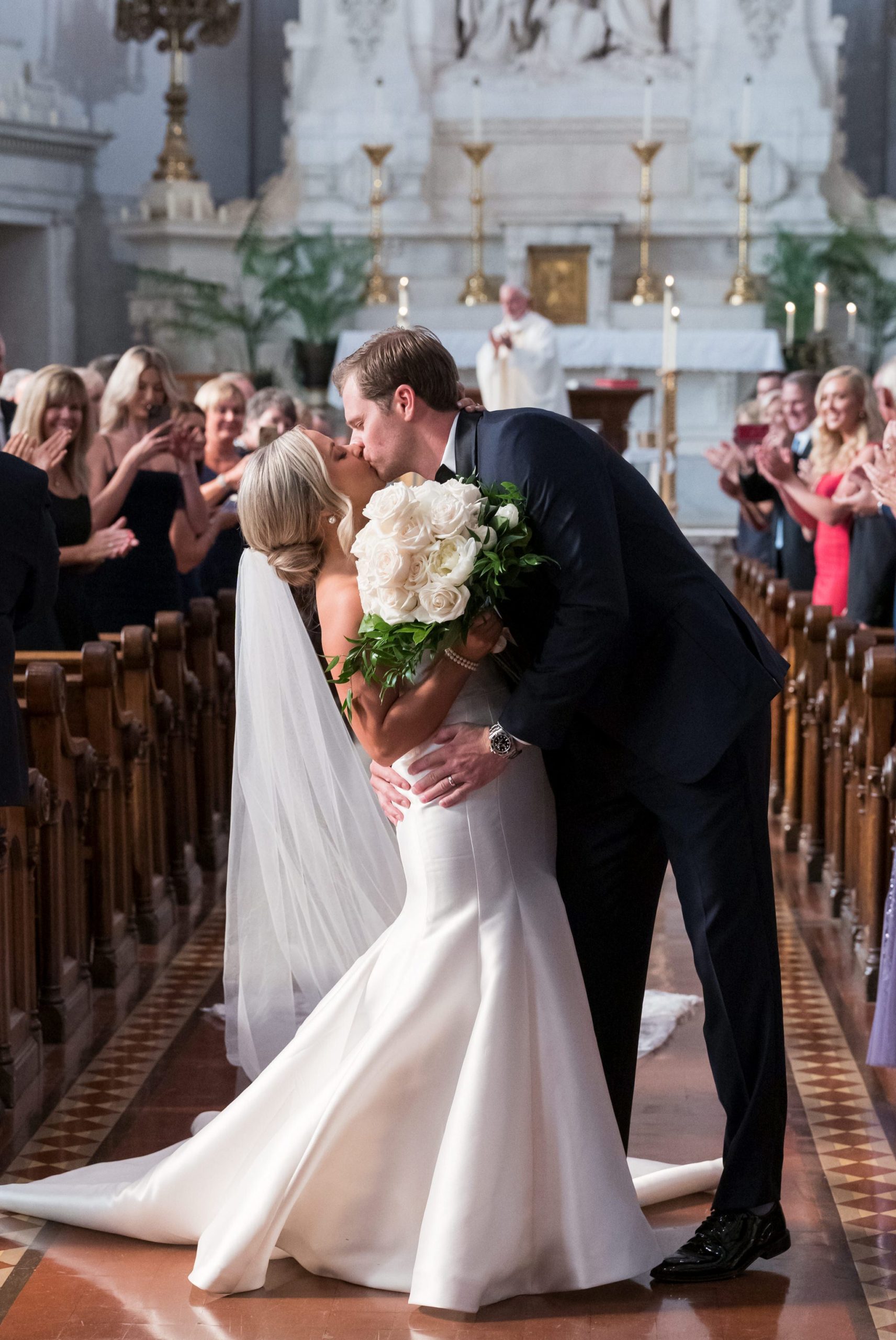 A bride and groom kiss while walking down the aisle at Saints Peter and Paul Jesuit Church Detroit.  