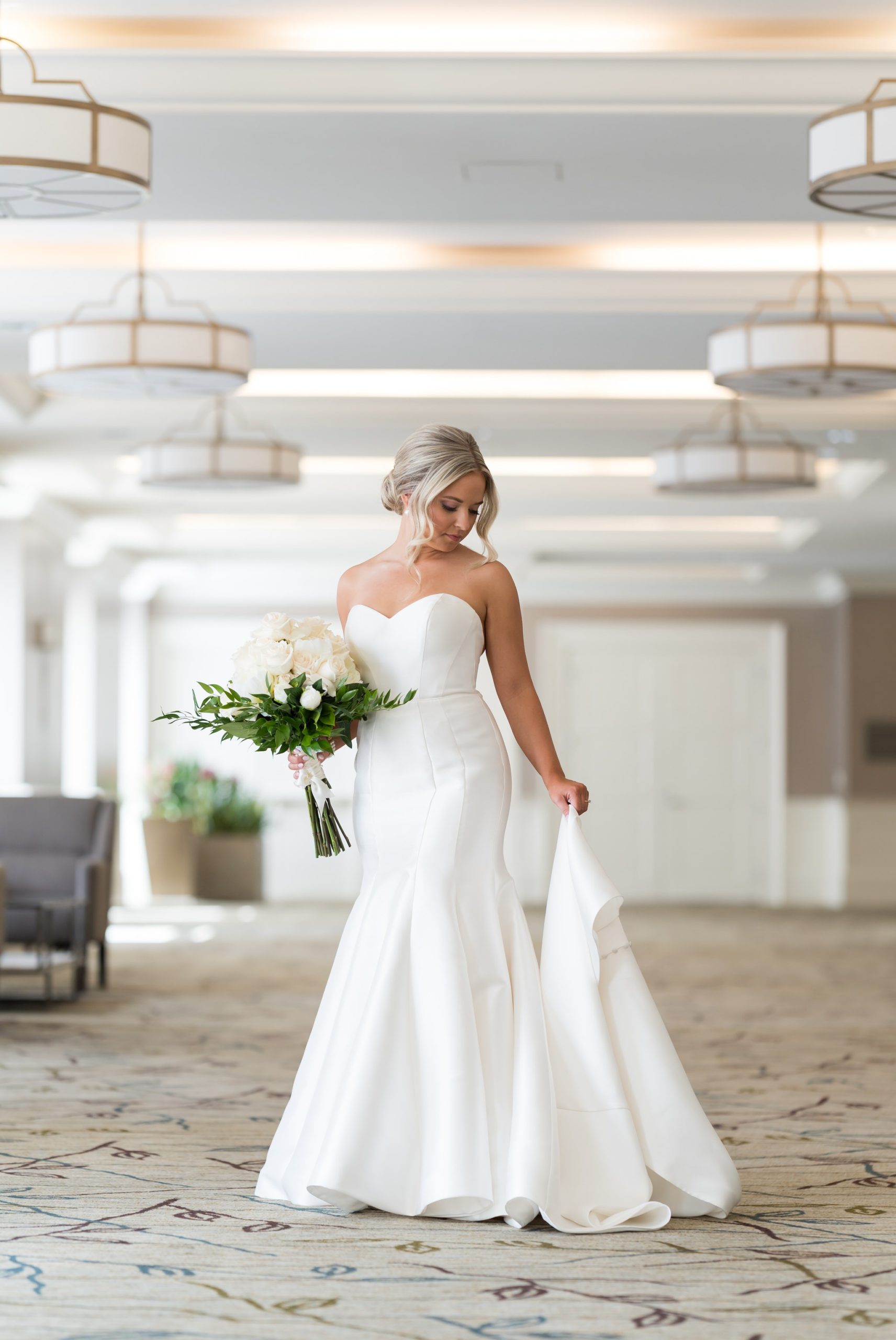 A bride holds her dress in a hotel lobby.  