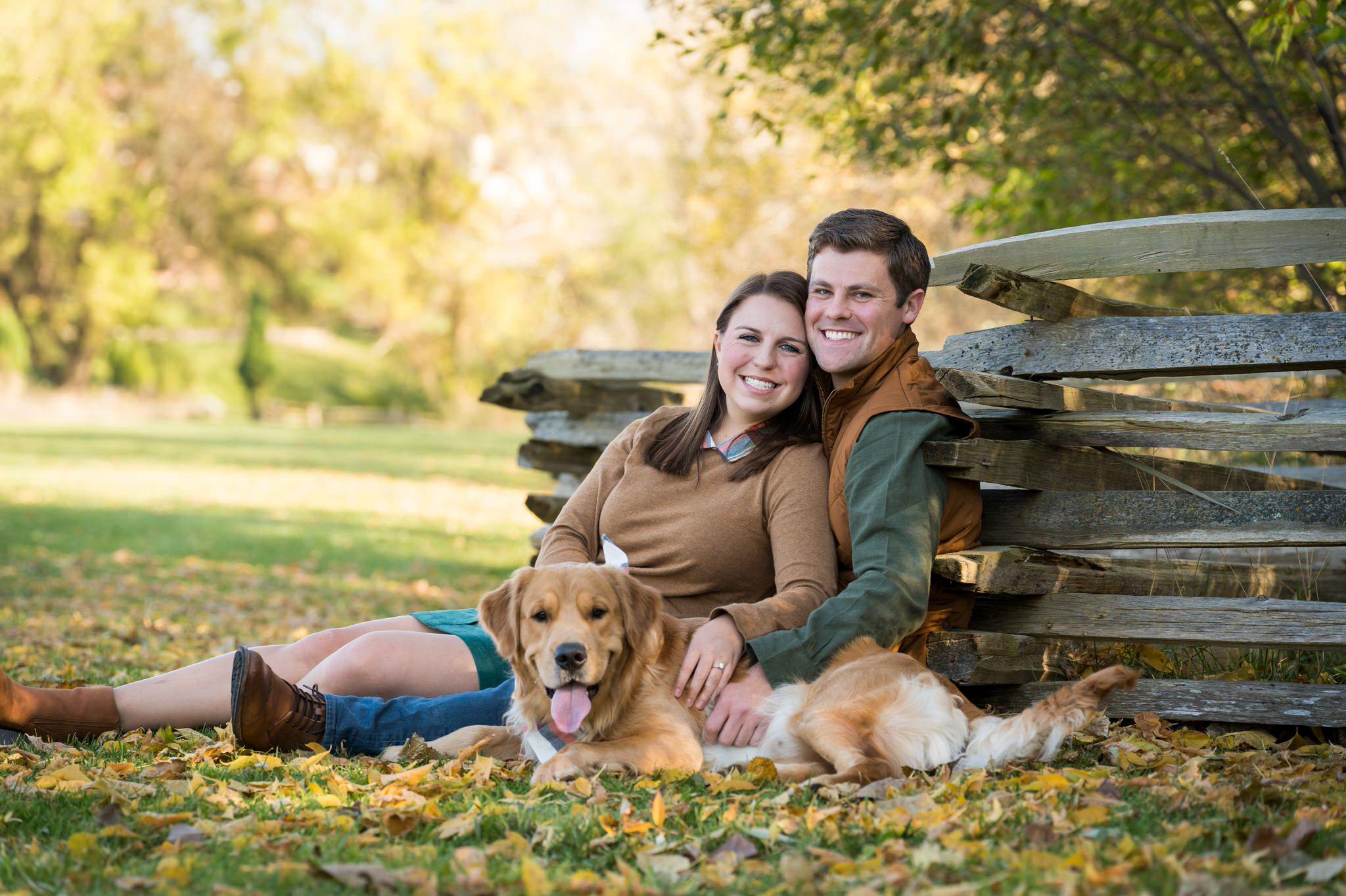A couple poses with their golden retriever dog at a fall engagement session at Van Hoosen. 