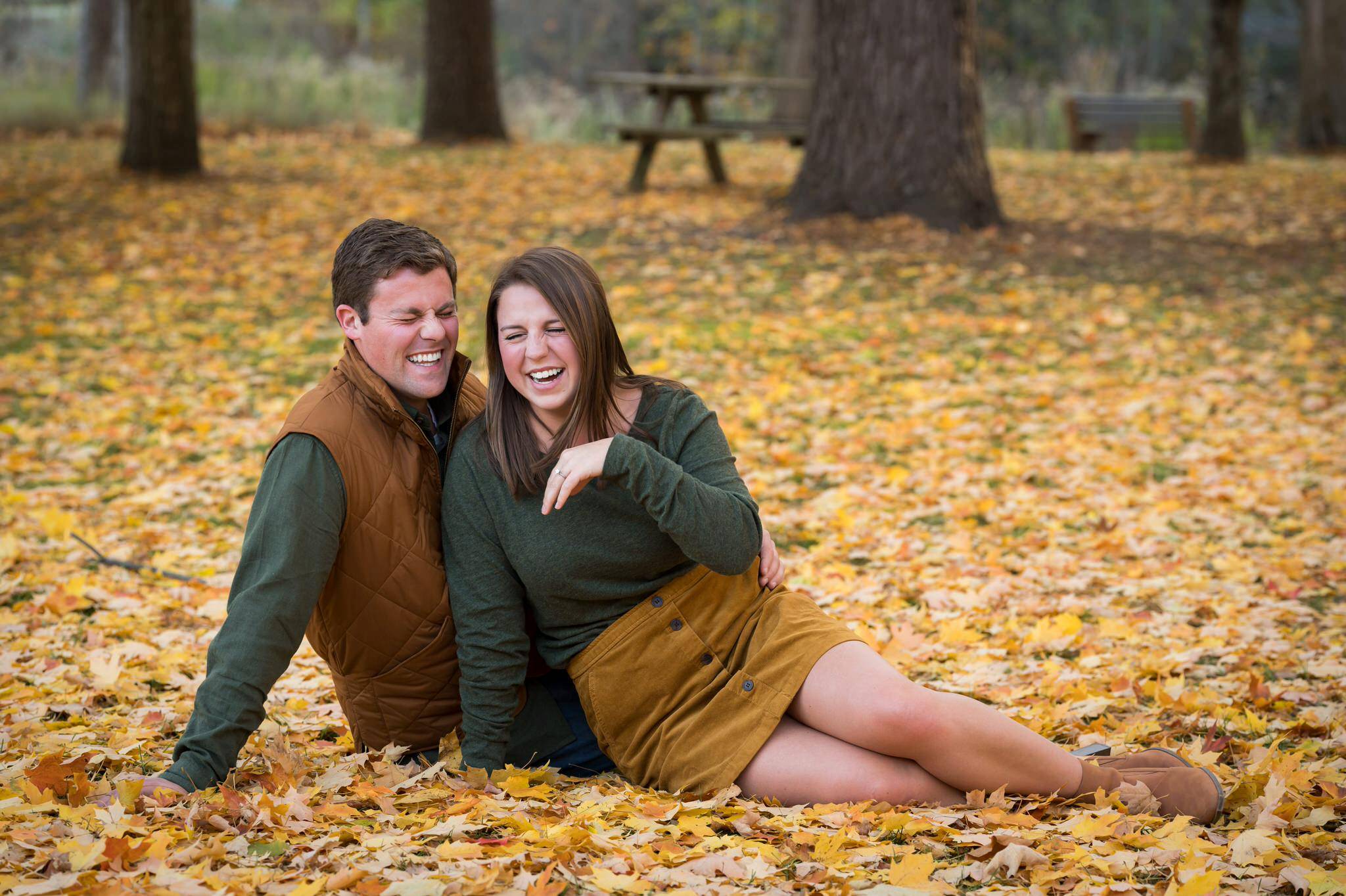 A couple, sitting on the ground, laughs during their fall engagement at Van Hoosen. 