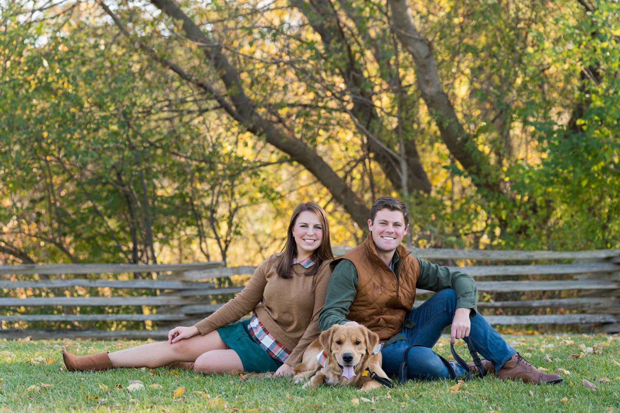 A couple poses with their golden retriever dog at a fall engagement session at Van Hoosen. 