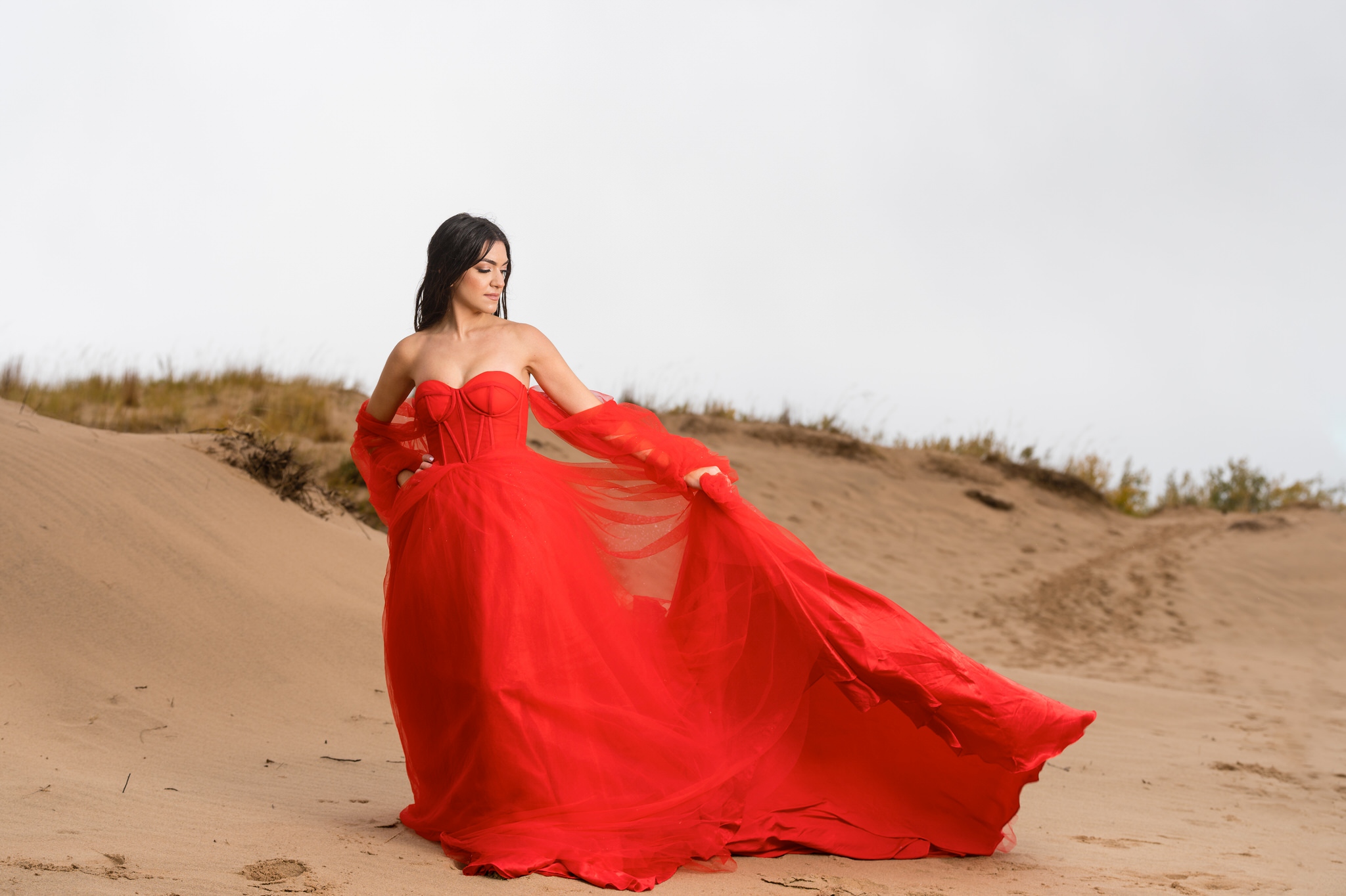 A woman wearing a red flowing dress at Sleeping Bear Dunes engagement session. 