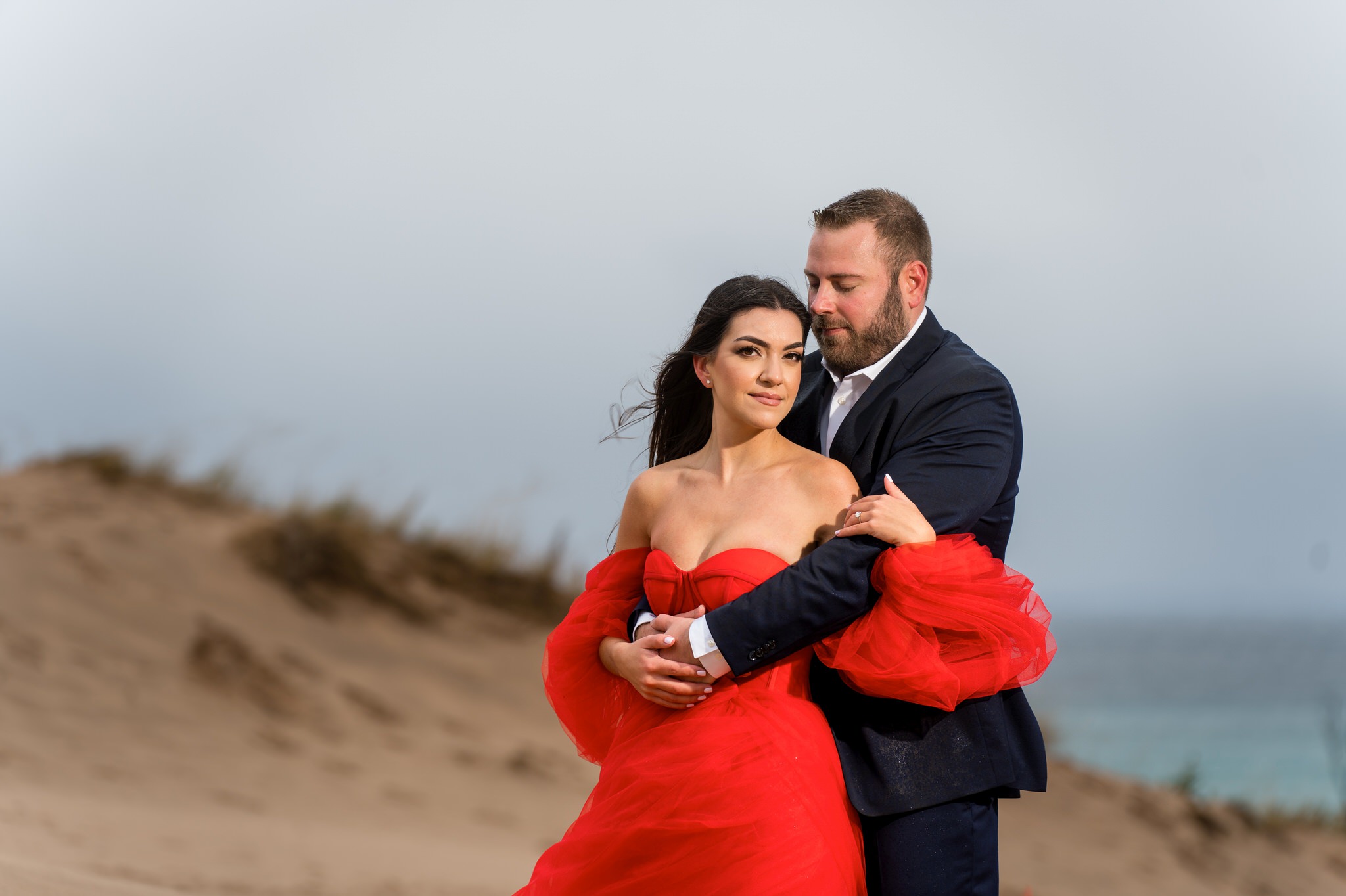 A portrait of a woman wearing a red dress during her Sleeping Bear Dunes engagement shoot.  