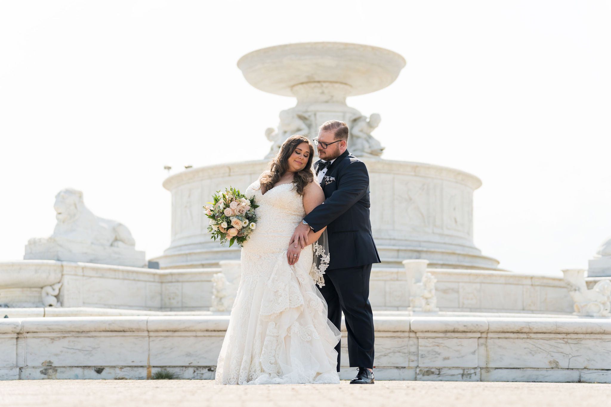 A groom hugs a bride from behind at  the Belle Isle Fountain, Detroit. 
