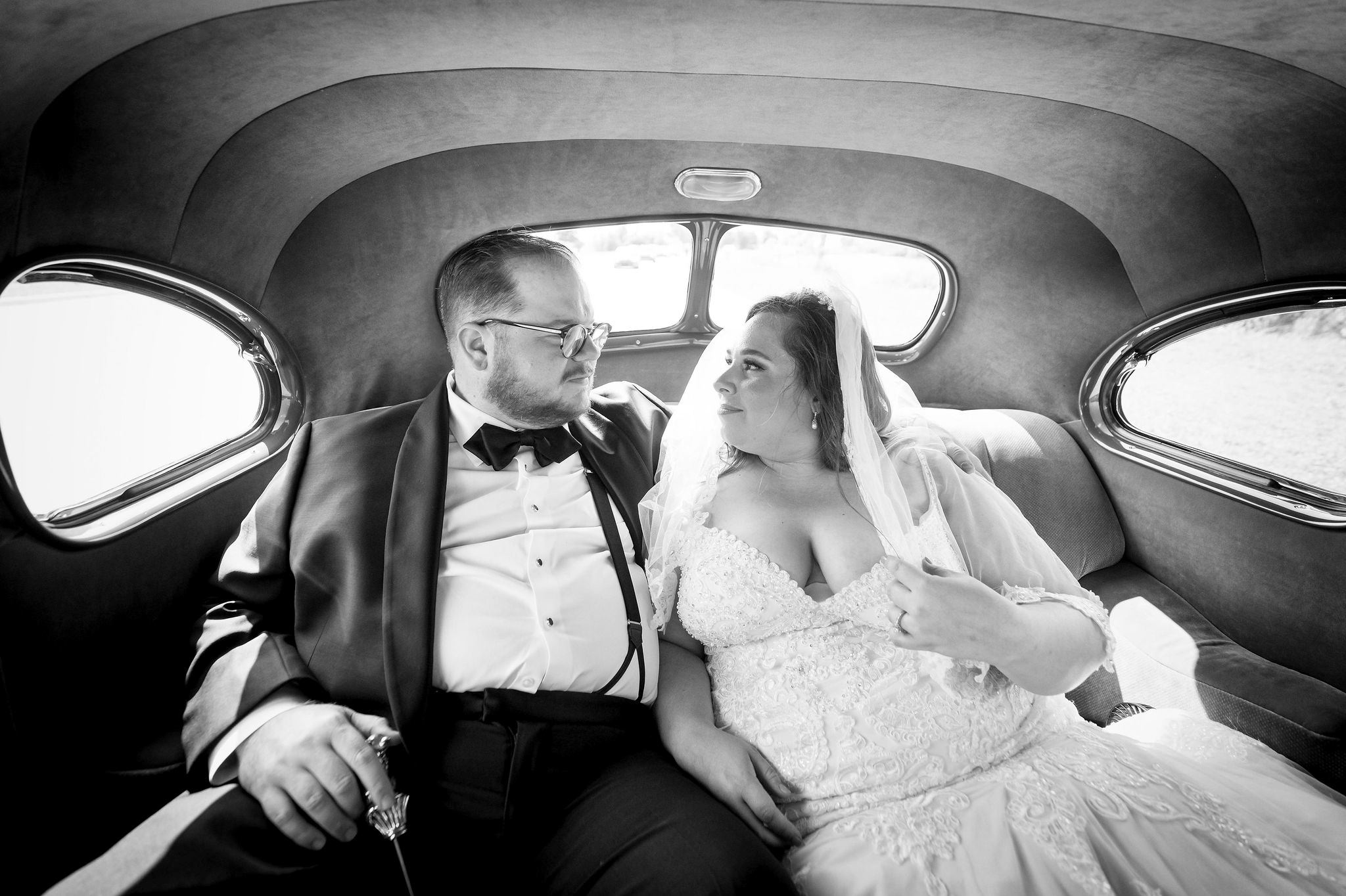 A couple rides in a classic car on their wedding day. 
