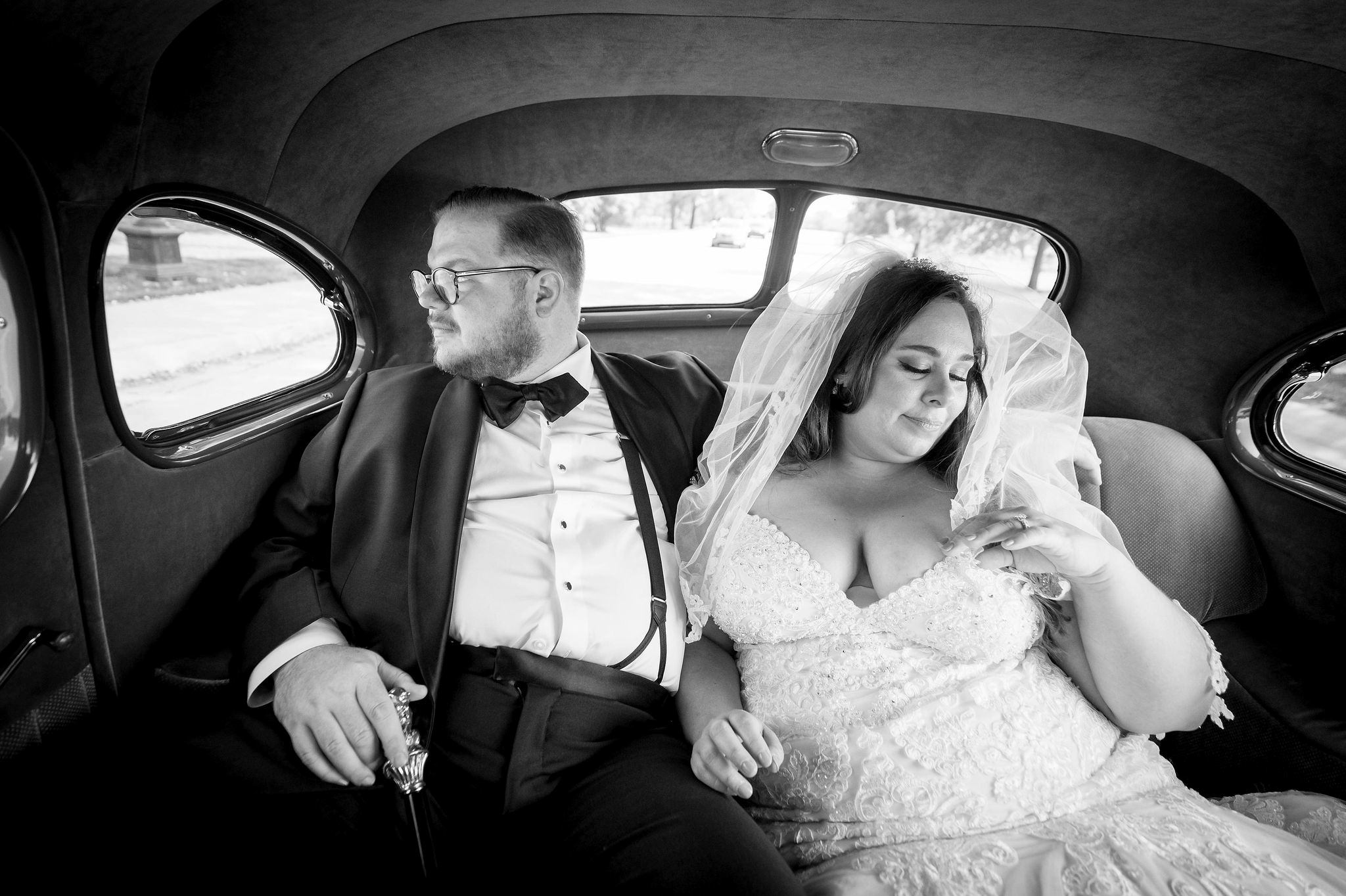 A couple rides in a classic car on their wedding day. 