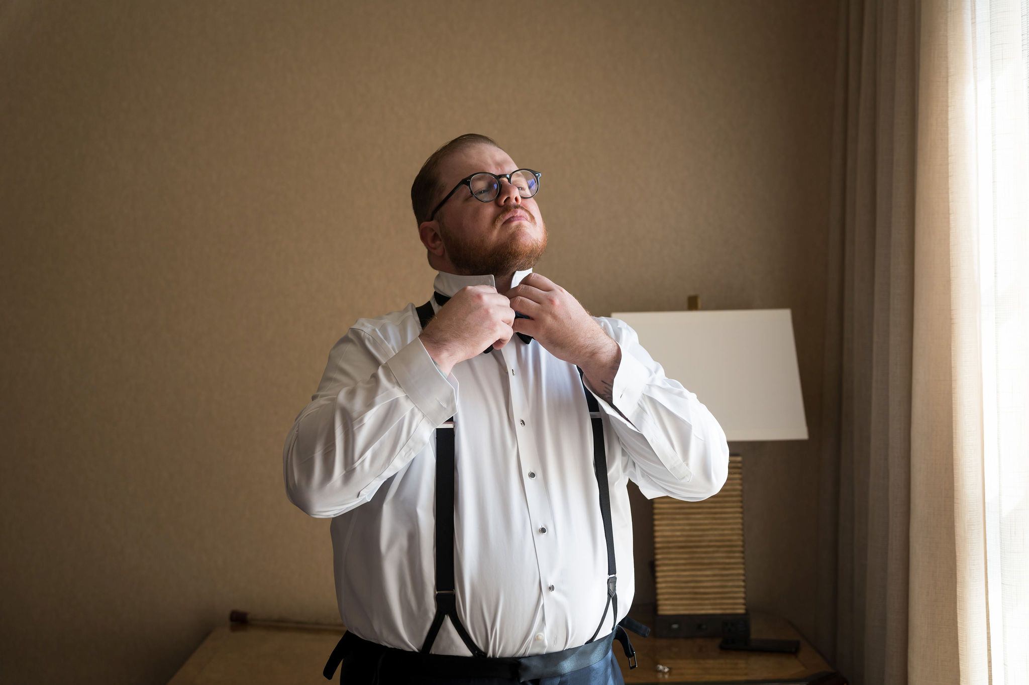A man fixes his bowtie in a hotel room of the Royal Park Hotel.