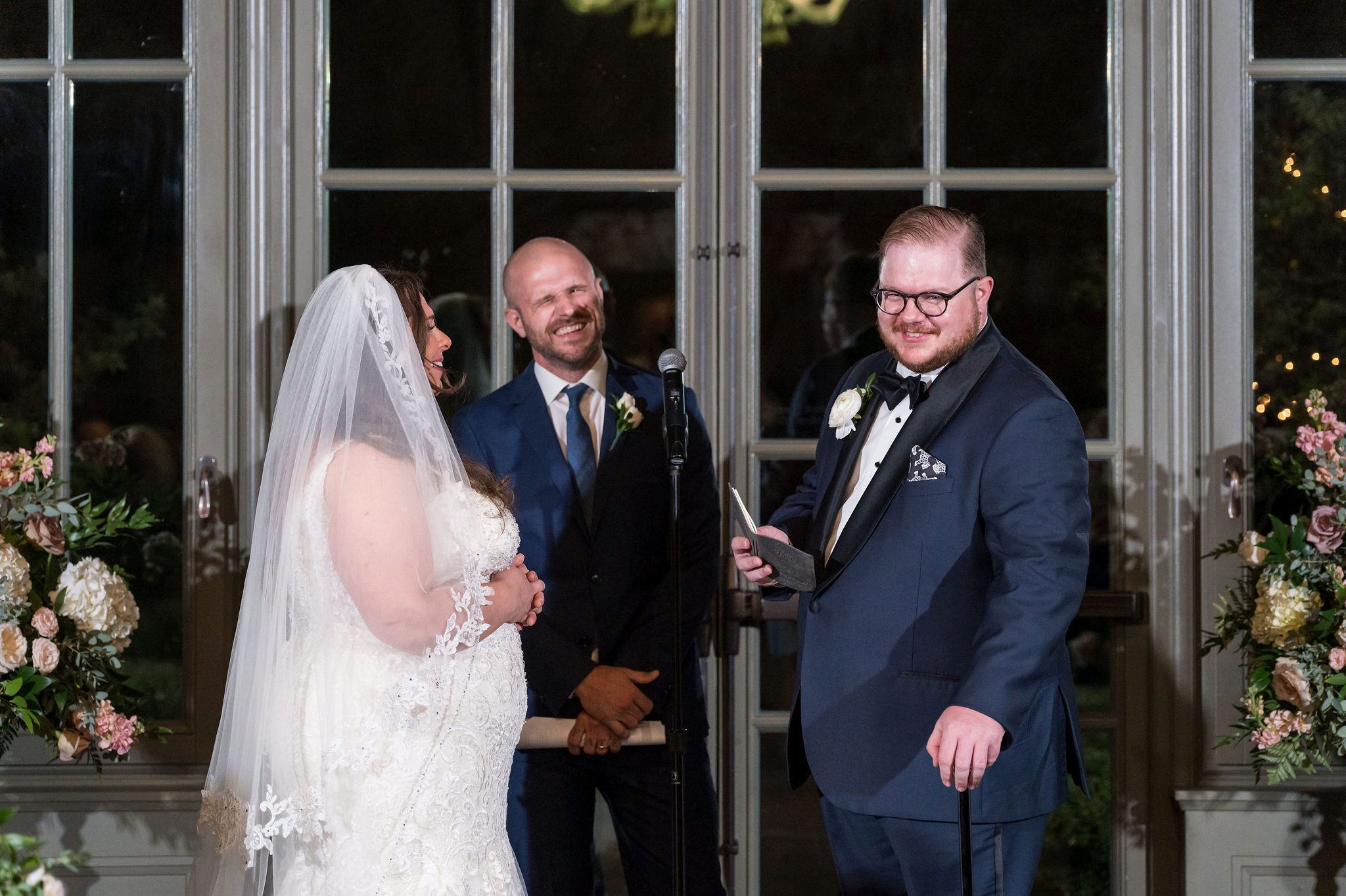 A bride and groom laugh while reading vows at their wedding at the Royal Park Hotel in Rochester, MI.