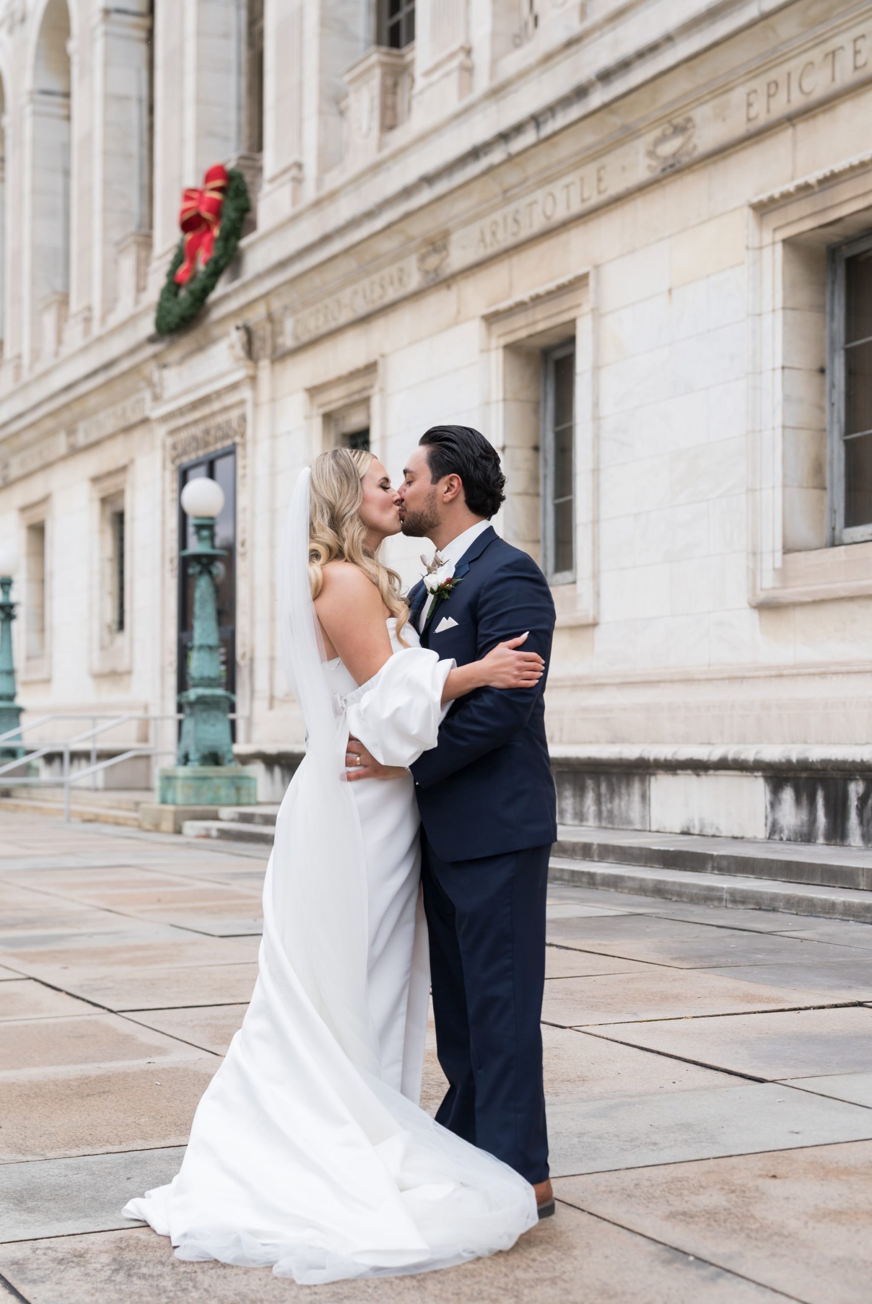 A couple embraces and kisses on their wedding day at the Detroit Public Library.