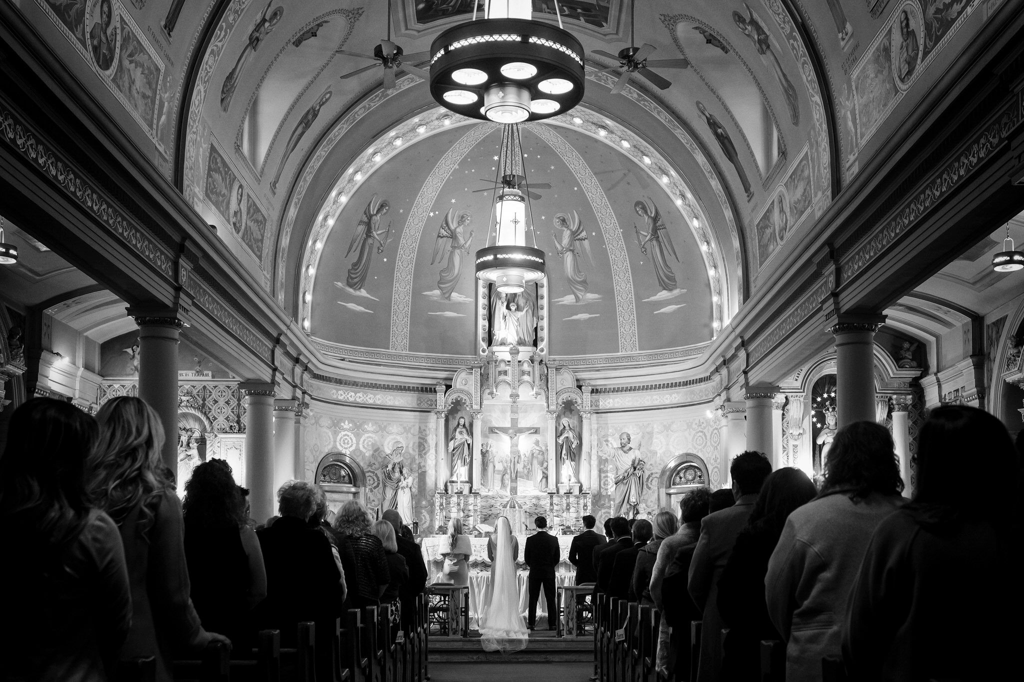 The bride and groom stand at the front of the church aisle on their wedding day.