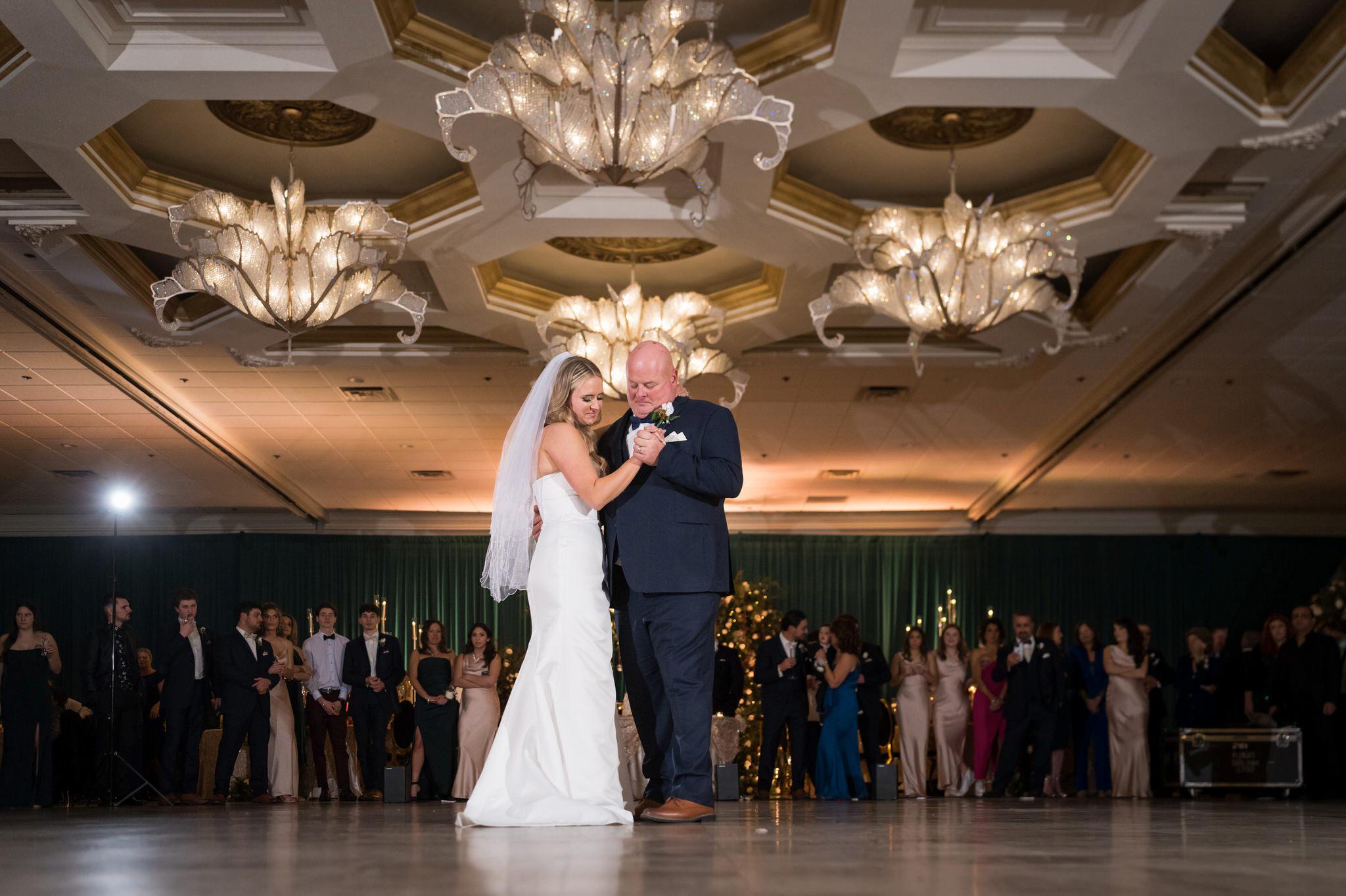The bride and her father dance under a chandelier at a Penna's of Sterling wedding reception. 