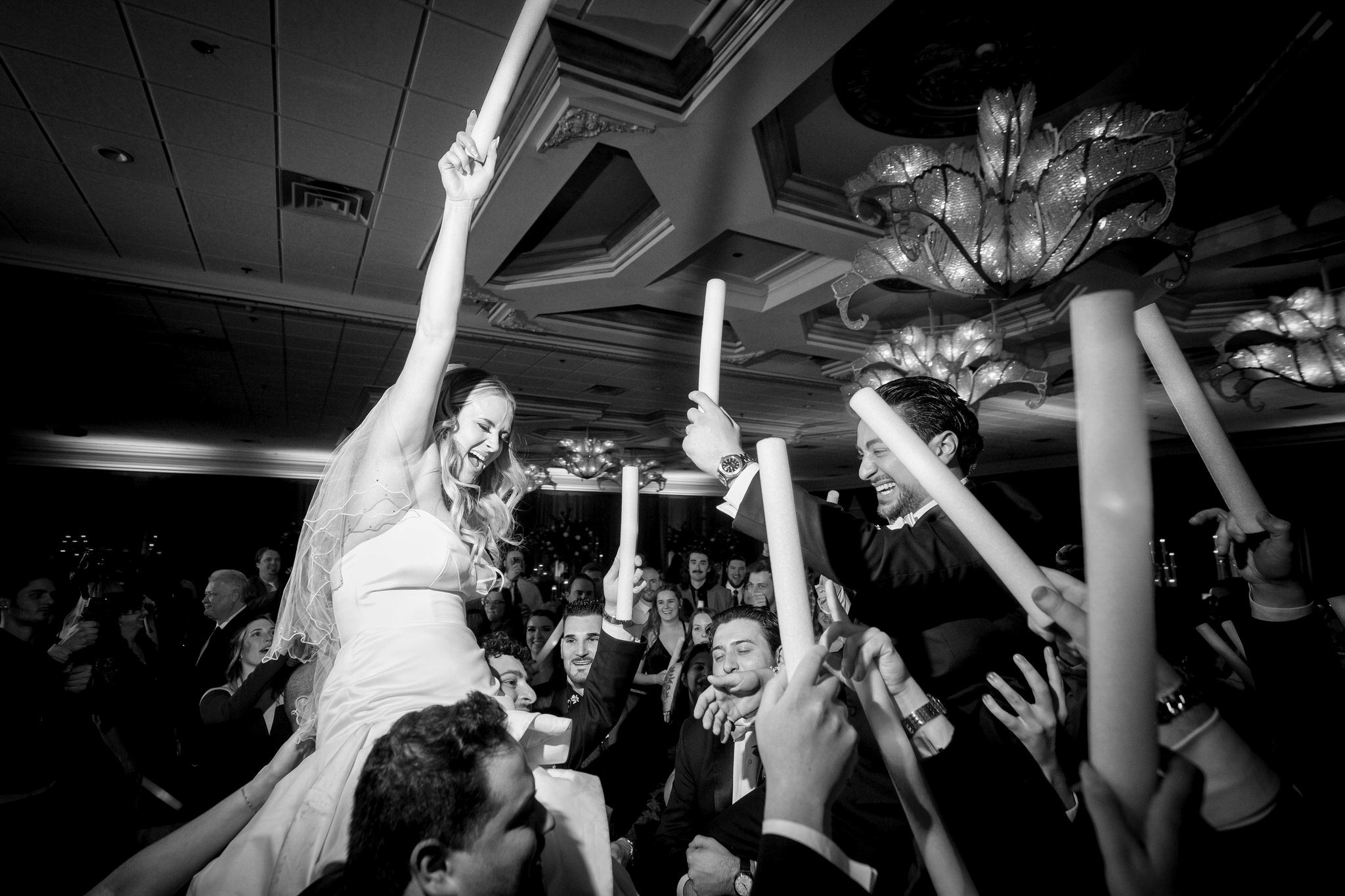 The bride and groom are lifted on the shoulders of groomsmen on the dance floor at a Penna's of Sterling wedding.