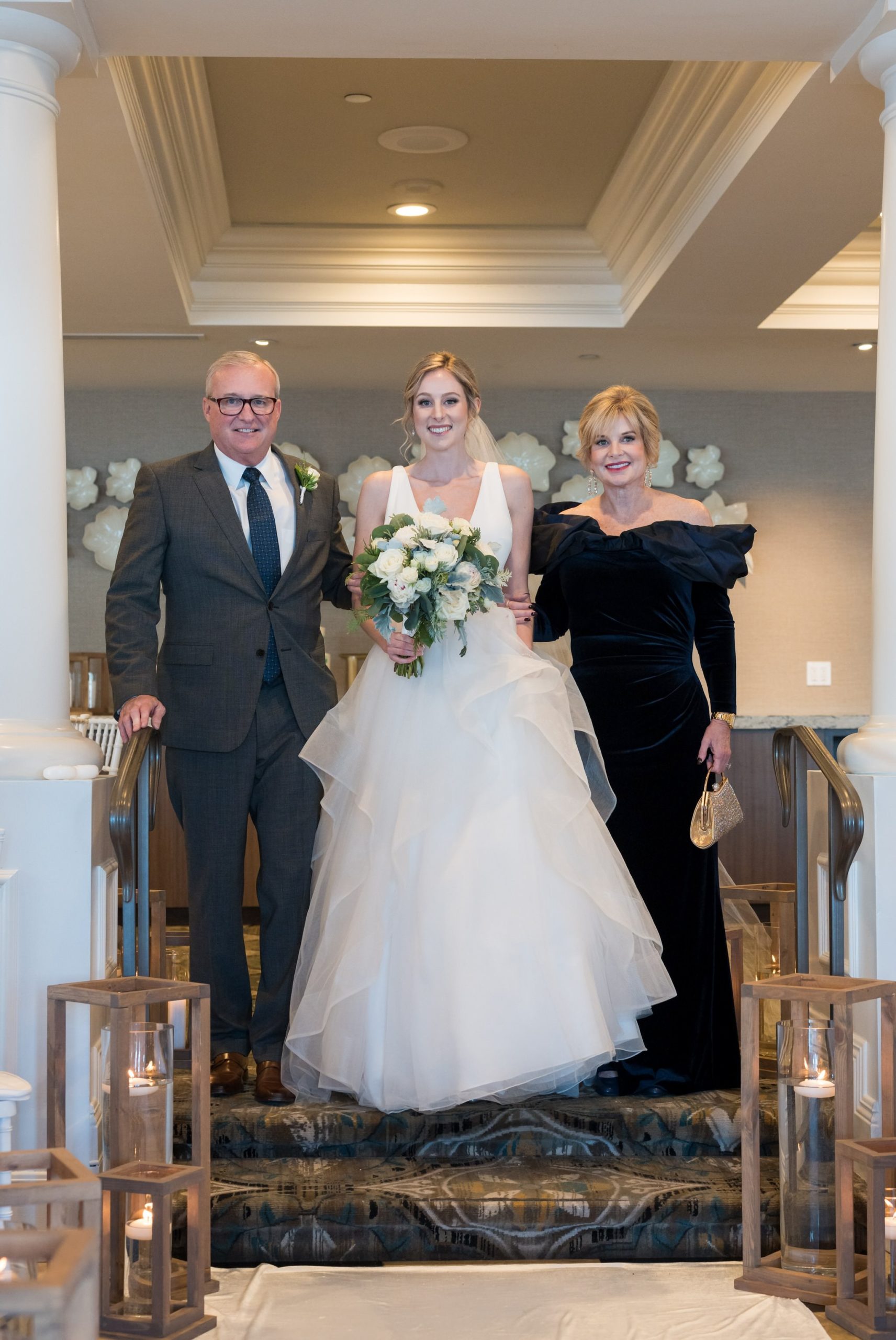 A bride is escorted by her parents down the aisle at her Bay Harbor wedding ceremony in the Sagamore Room. 